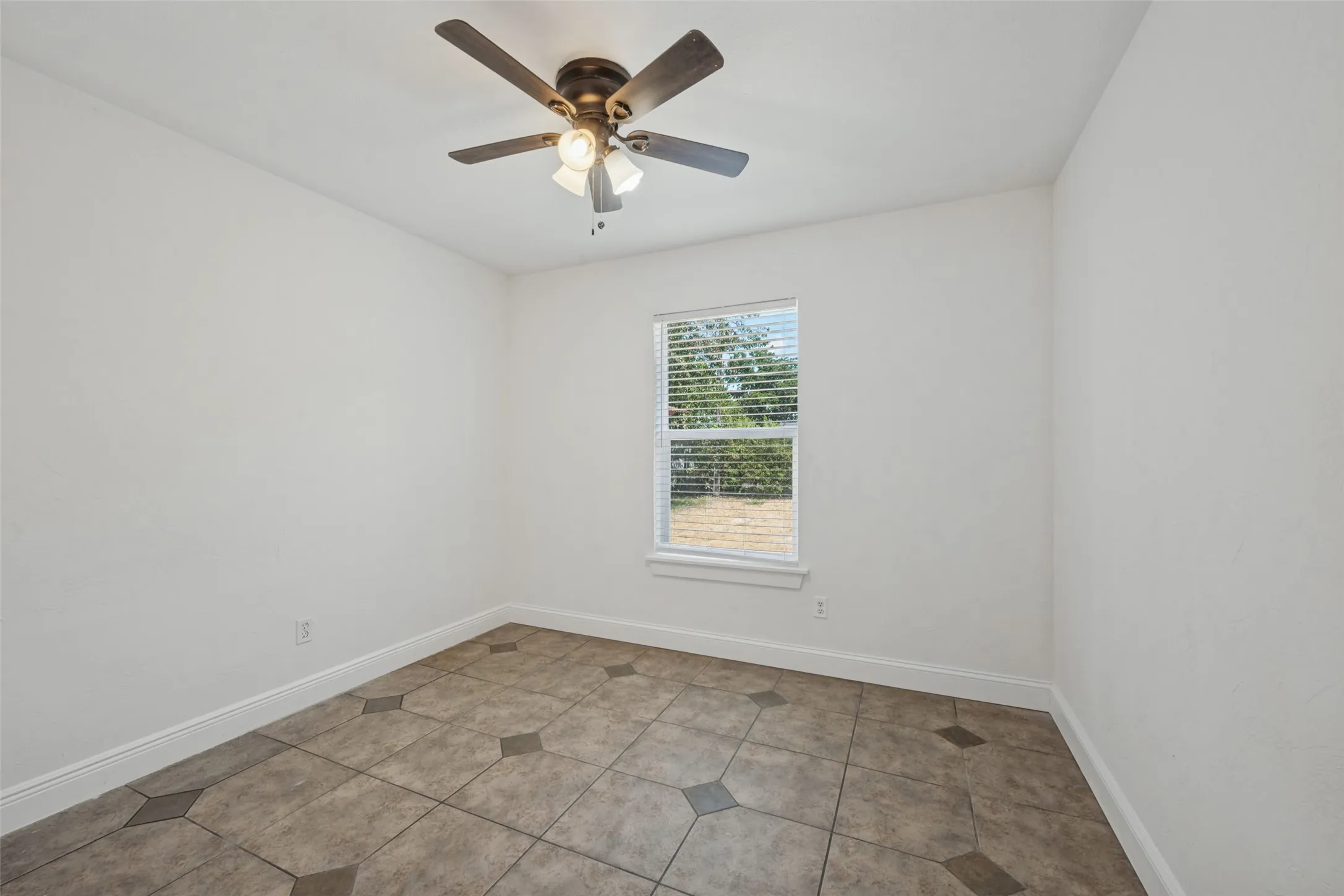Recessed window with blinds, ceiling fan with integrated lighting, and tile flooring with accent inserts