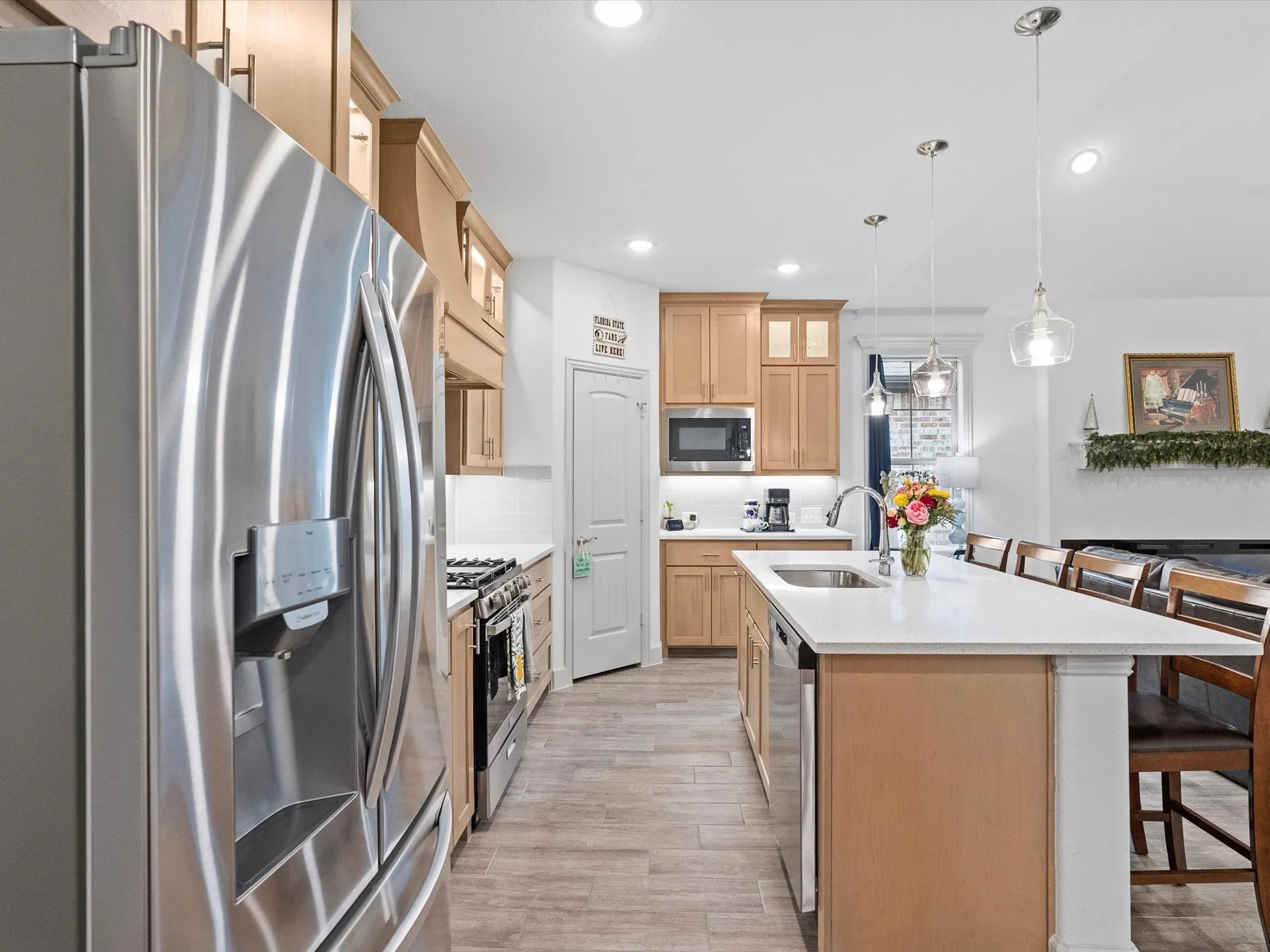 Kitchen featuring stainless steel appliances, light wood-finish cabinetry, white countertops, tile flooring, and pendant lighting
