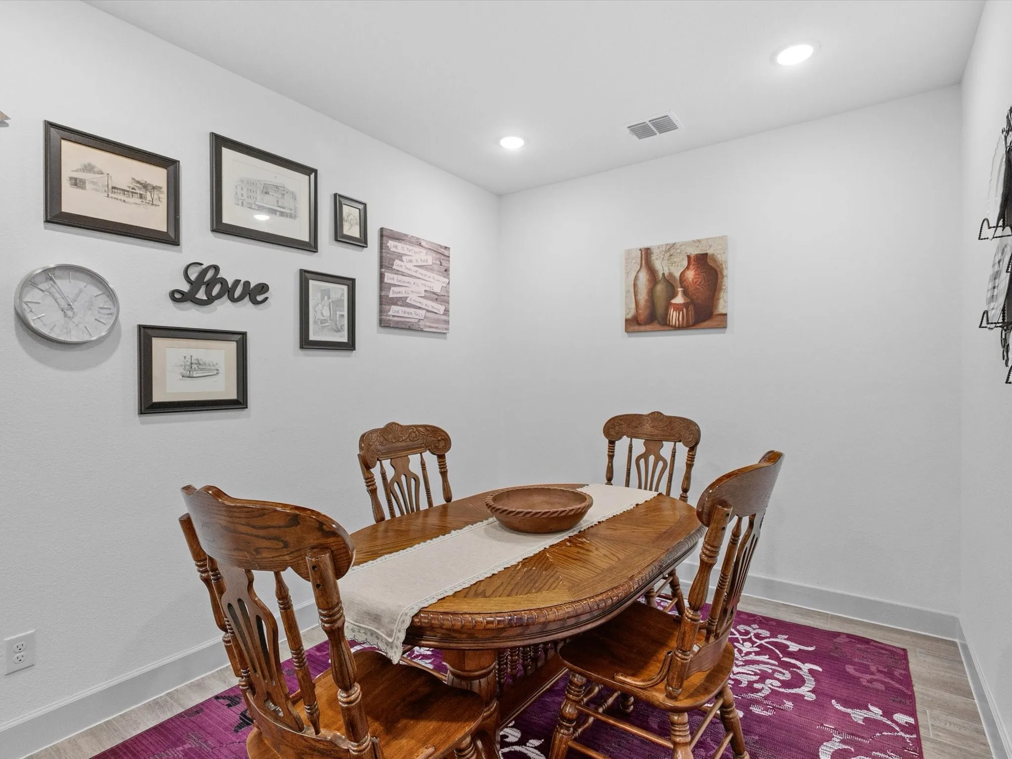 Recessed lighting illuminates a dining area with light wood-finish flooring