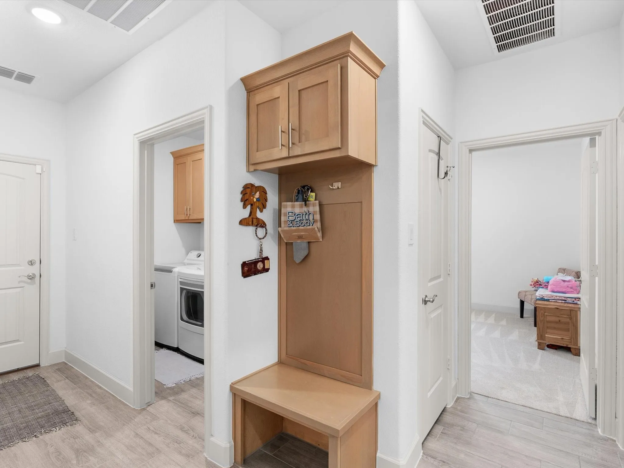 Built-in hall tree with storage, wood-finish flooring, recessed lighting, and a utility room with built-in cabinetry