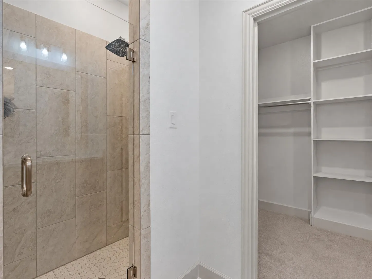 Glass-enclosed shower with large format wall tiles and hexagonal floor tiles