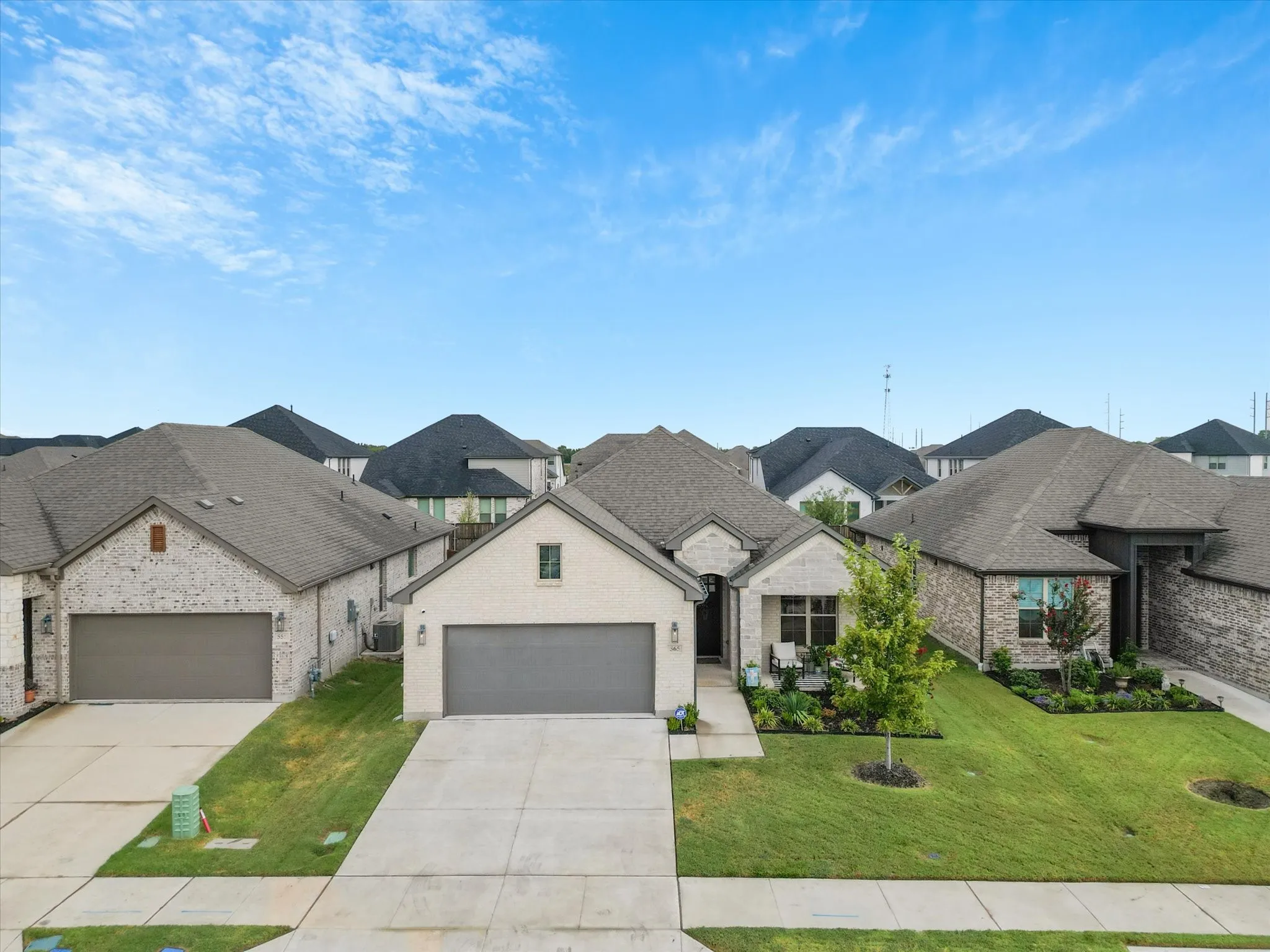 Brick and stone exterior, attached two-car garage, concrete driveway, landscaped front yard, covered porch entry