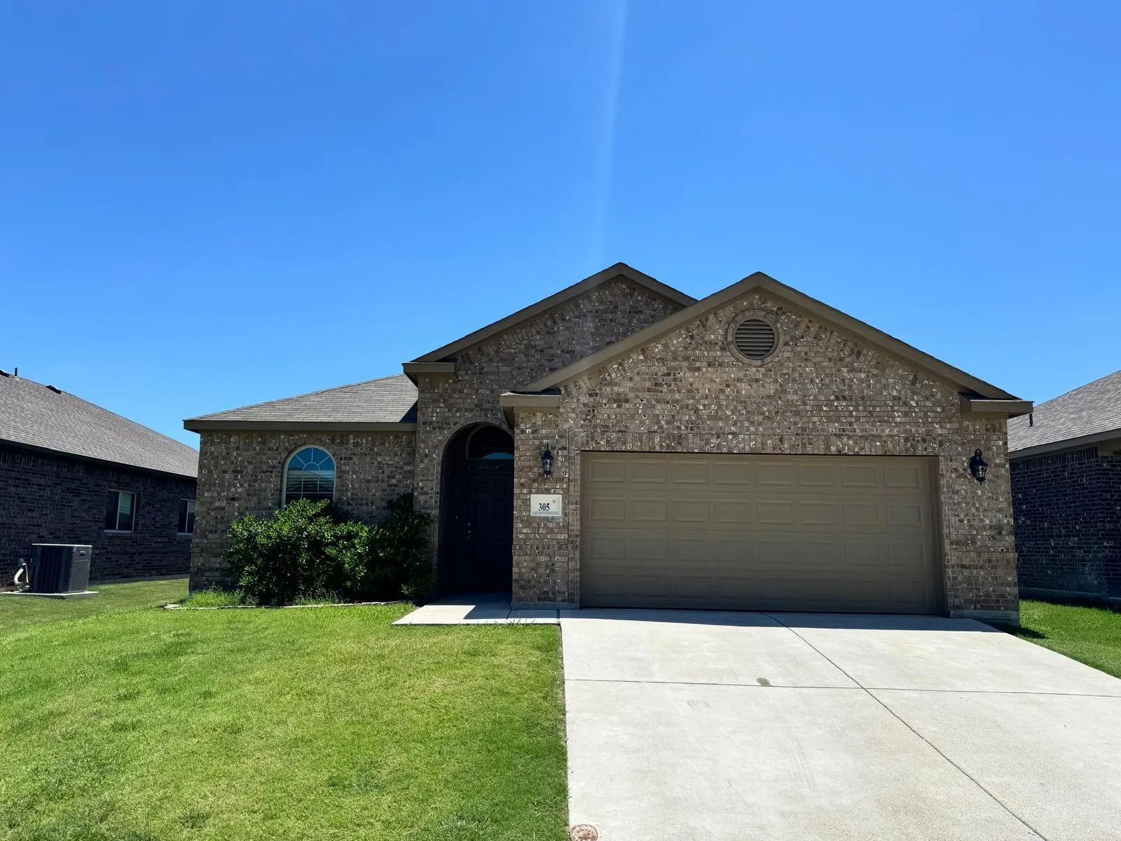 View of front facade featuring a garage, a front lawn, and central air condition unit