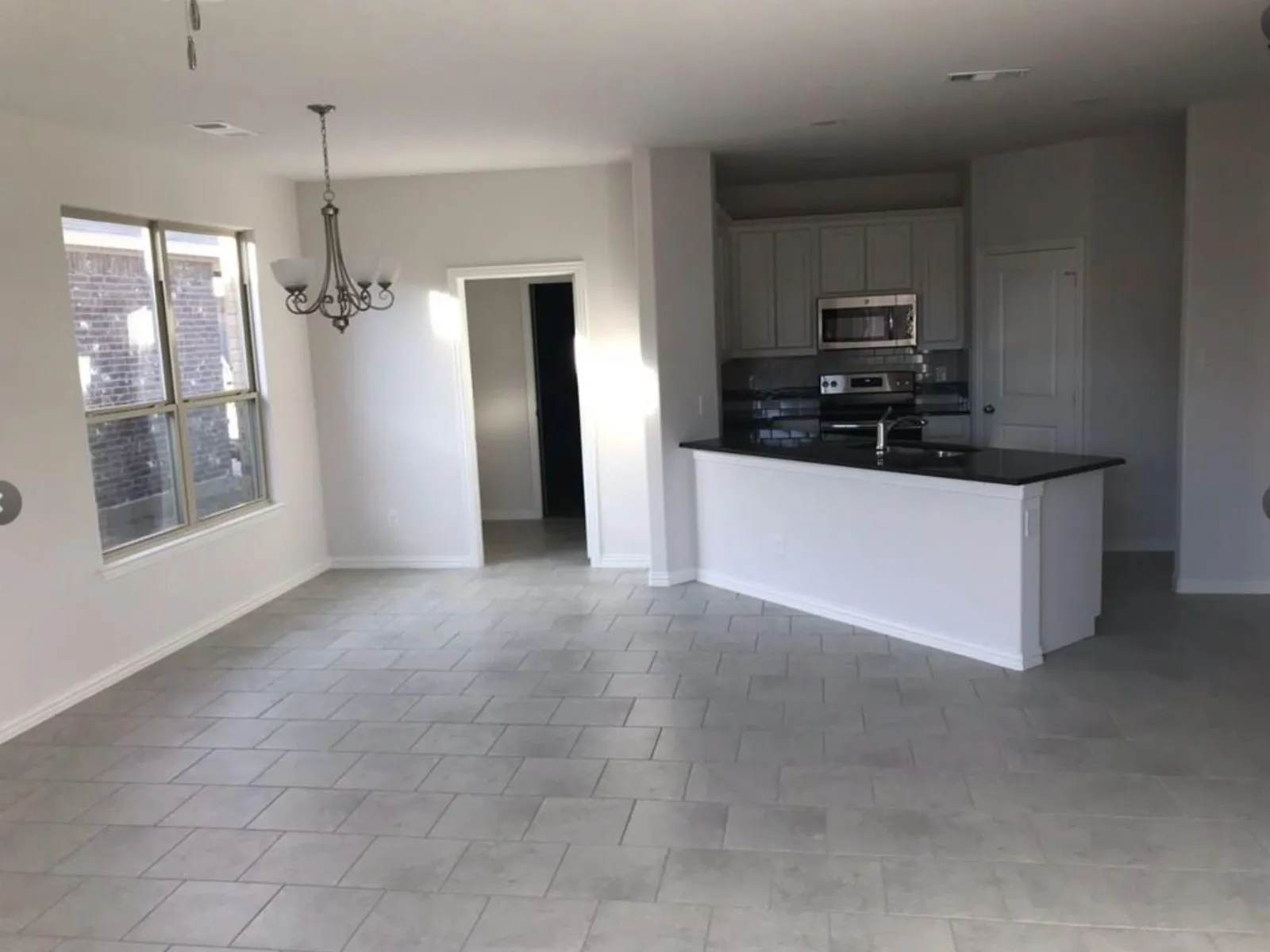 Kitchen featuring hanging light fixtures, appliances with stainless steel finishes, tile floors, a notable chandelier, and sink