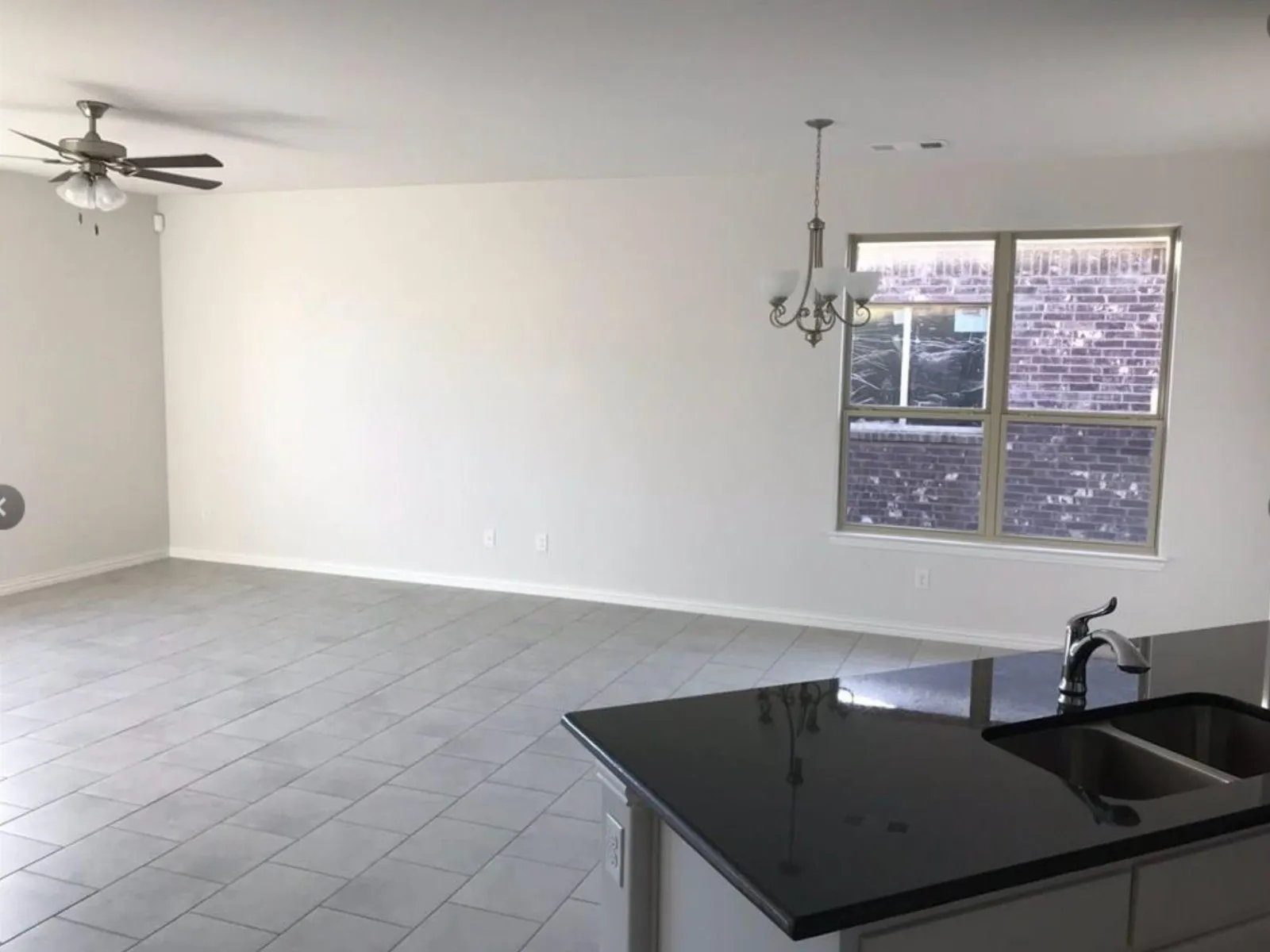 Kitchen with decorative light fixtures, sink, tile flooring, and ceiling fan with notable chandelier