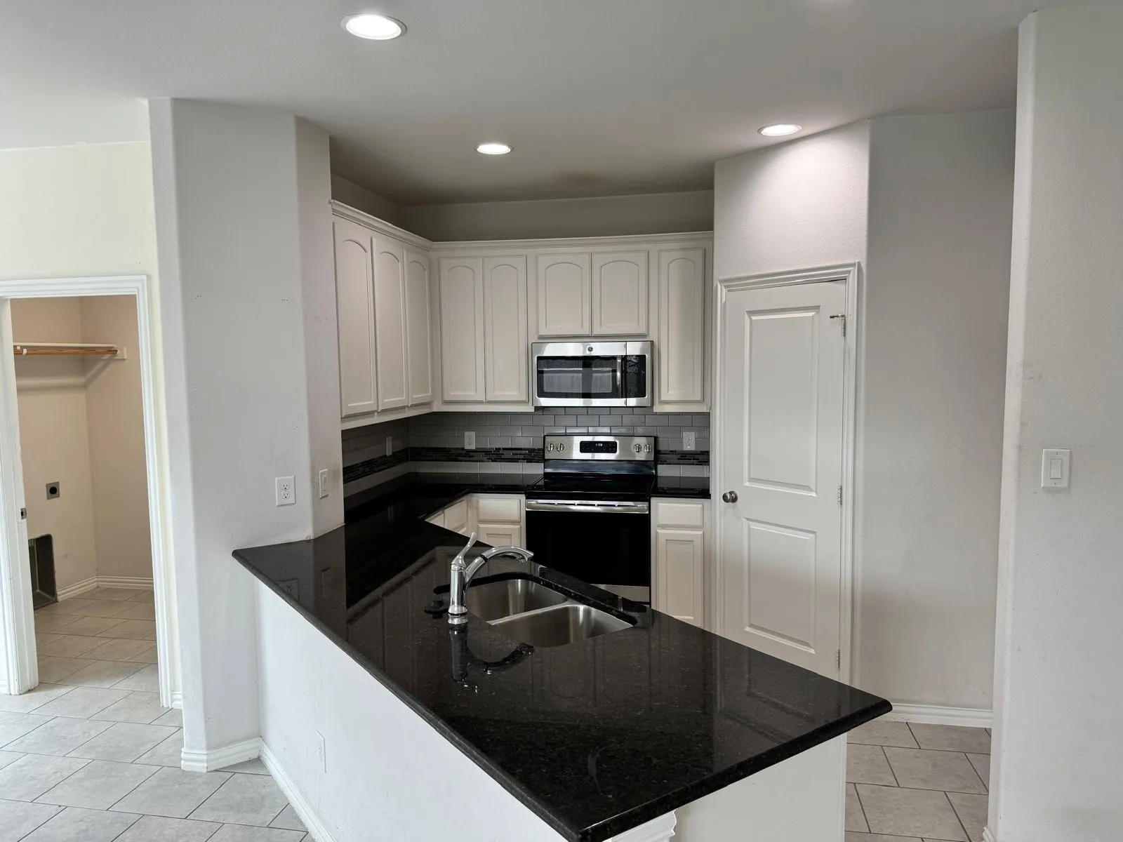 Kitchen featuring backsplash, white cabinetry, appliances with stainless steel finishes, sink, and light tile floors
