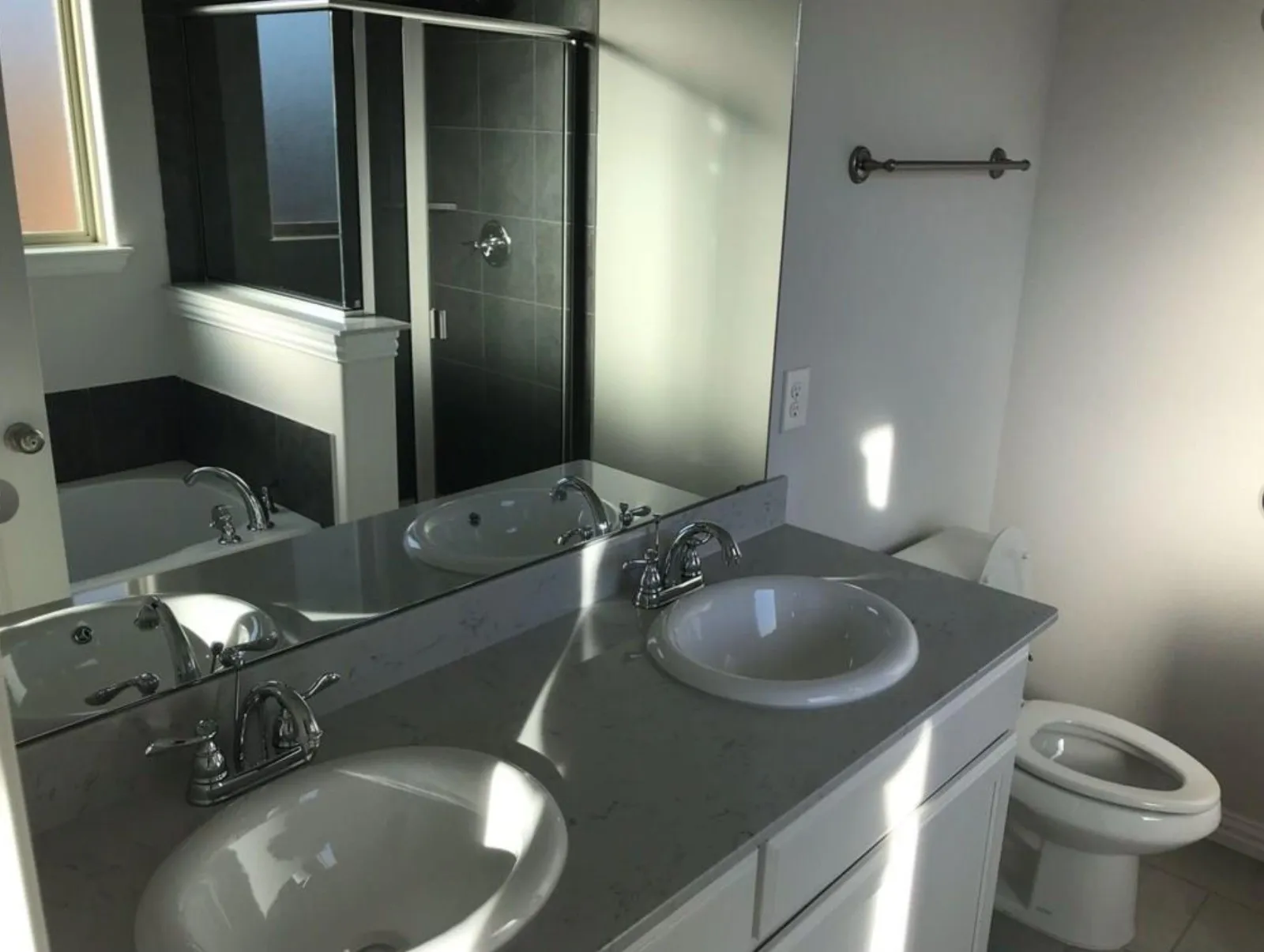 Full bathroom featuring dual bowl vanity, toilet, tile floors, and plus walk in shower