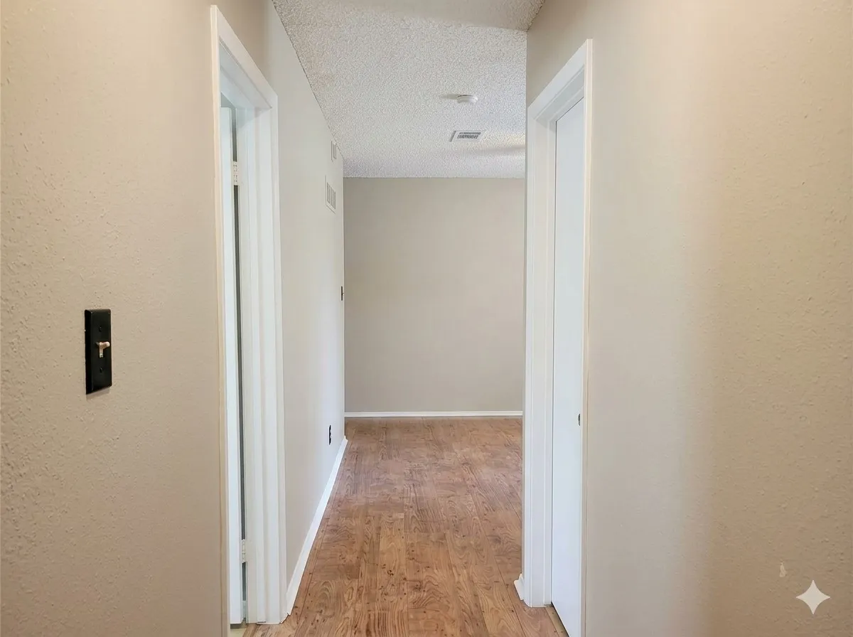 Hallway featuring wood-finish flooring, light neutral wall paint, and white trim