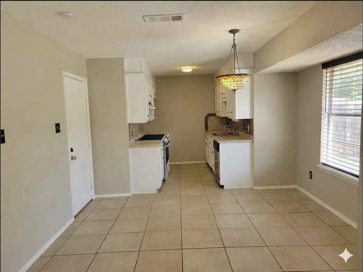 Kitchen space featuring tile flooring, white cabinetry, a built-in range, a sink with a backsplash, and a window with blinds