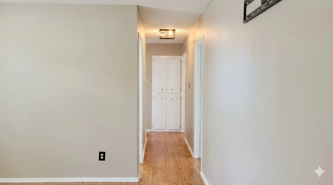 Wood-finish flooring extending through a neutral-toned hallway with white paneled cabinetry