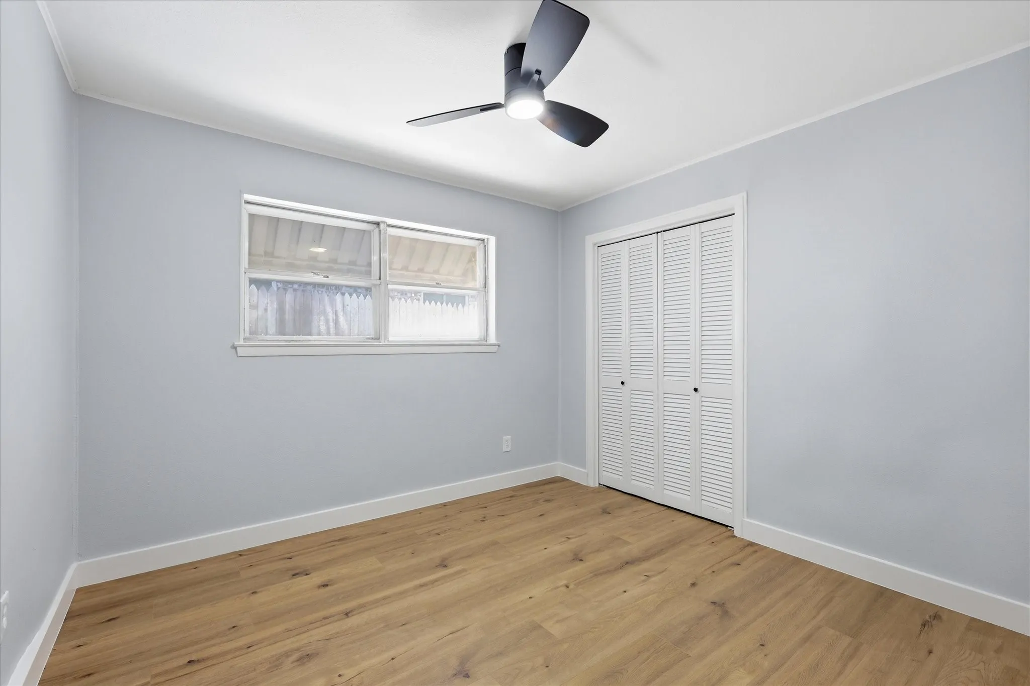 Room featuring wood-finish flooring, light grey walls, and white trim