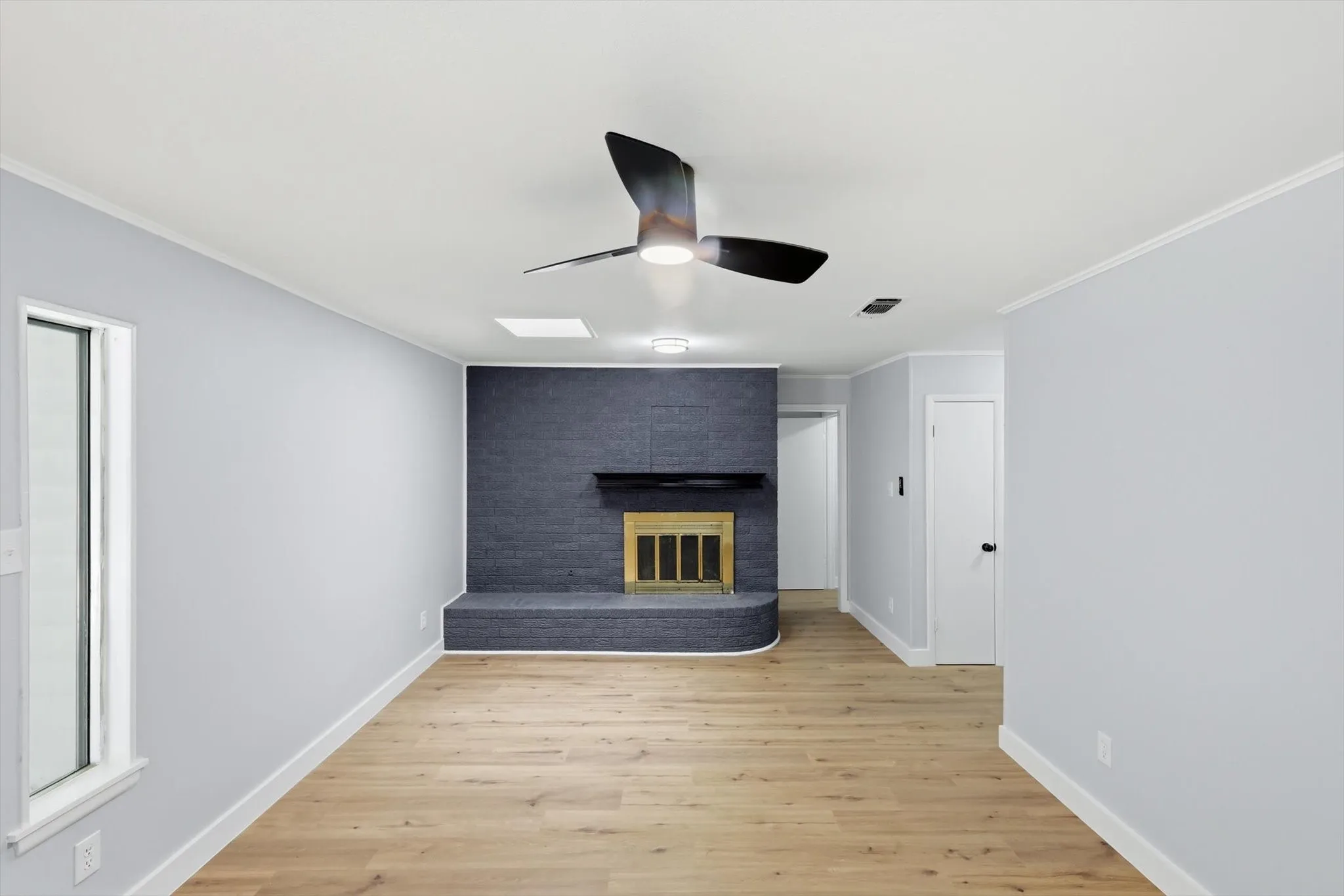 Living area featuring wood-finish flooring, light gray wall paint, and a modern ceiling fan with integrated lighting