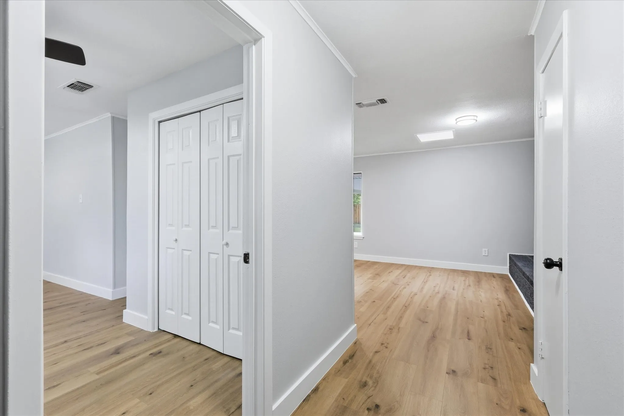 Hallway featuring wood-finish flooring, white bi-fold closet doors, and recessed lighting