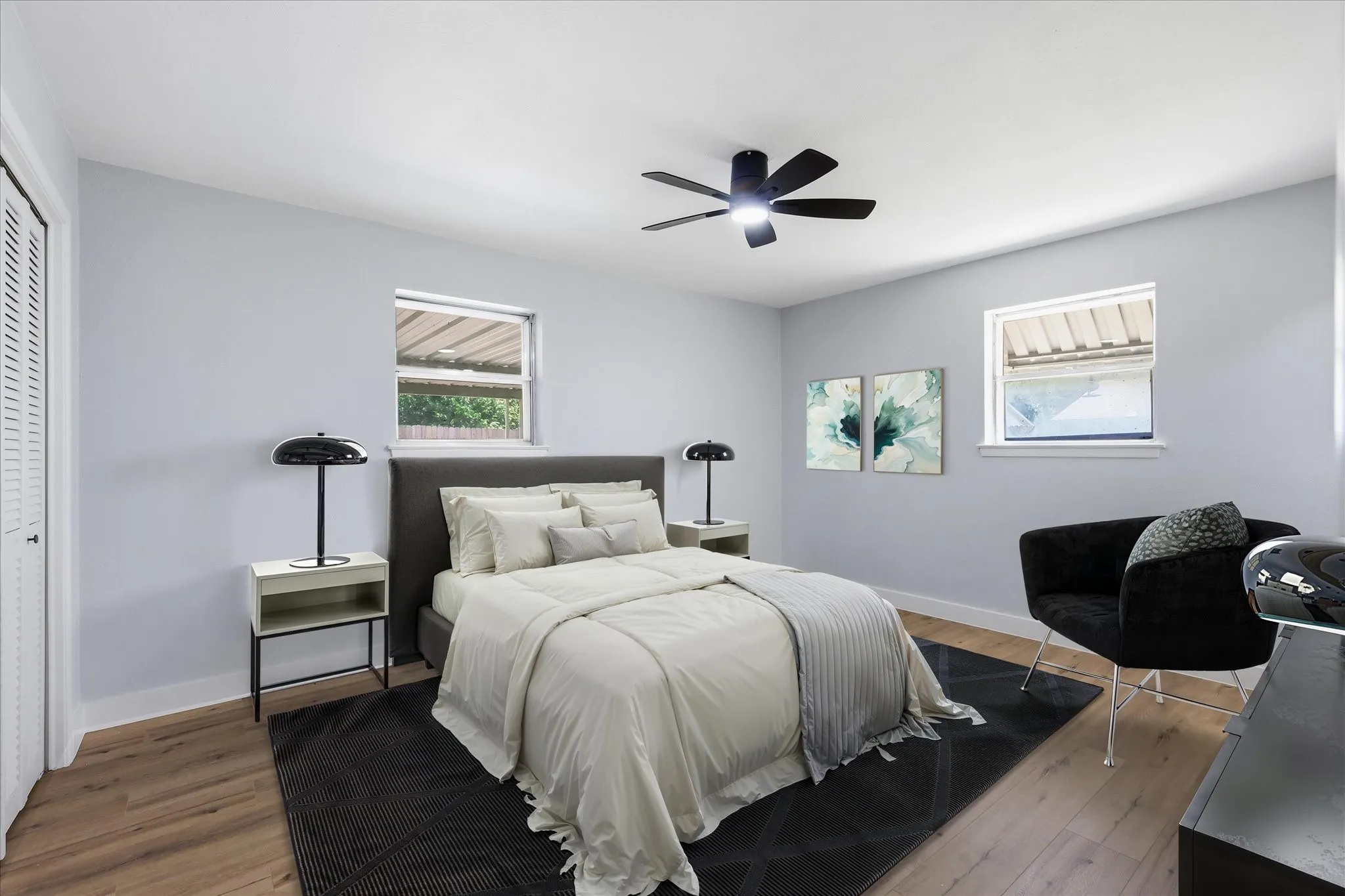 Spacious room featuring light-toned walls, wood-finish flooring, and a ceiling fan with integrated lighting