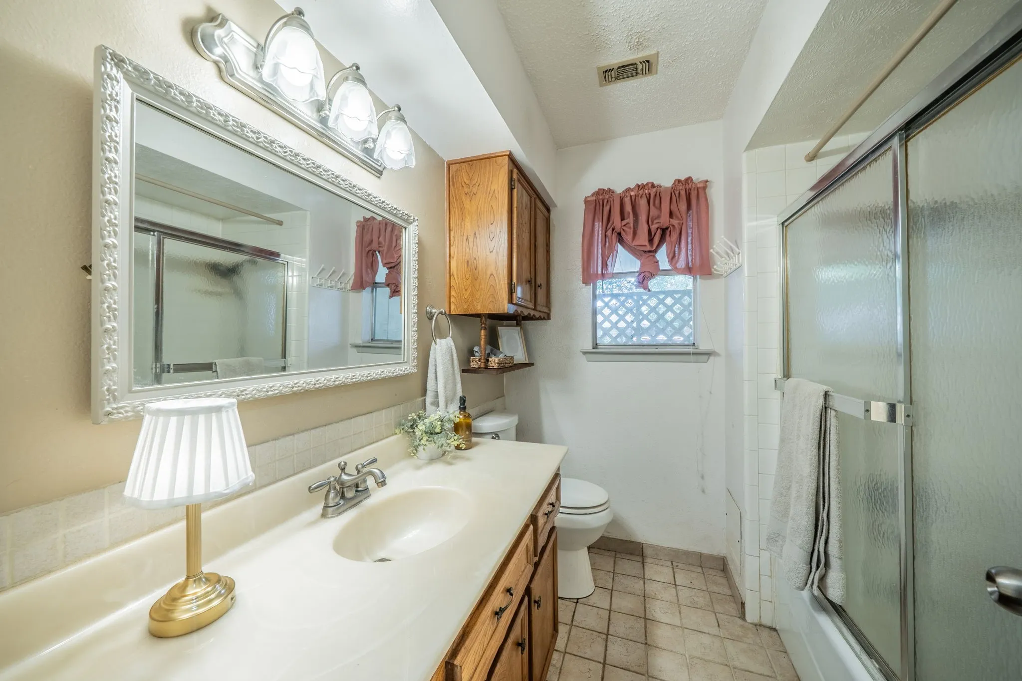 Vanity with integrated sink, wood-finish cabinetry, and framed mirror