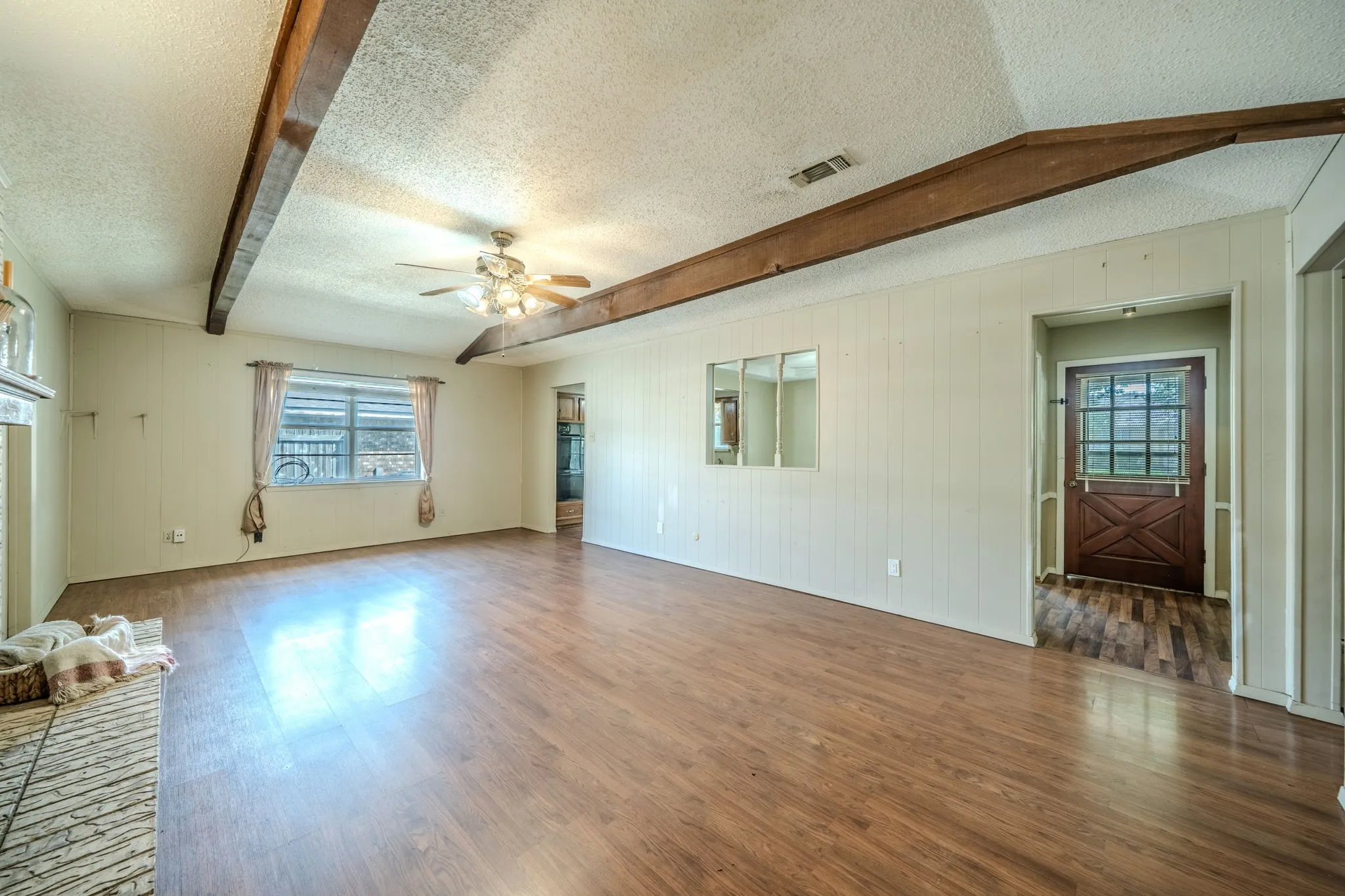 Exposed ceiling beams, wood-finish flooring, ceiling fan, and a built-in fireplace hearth