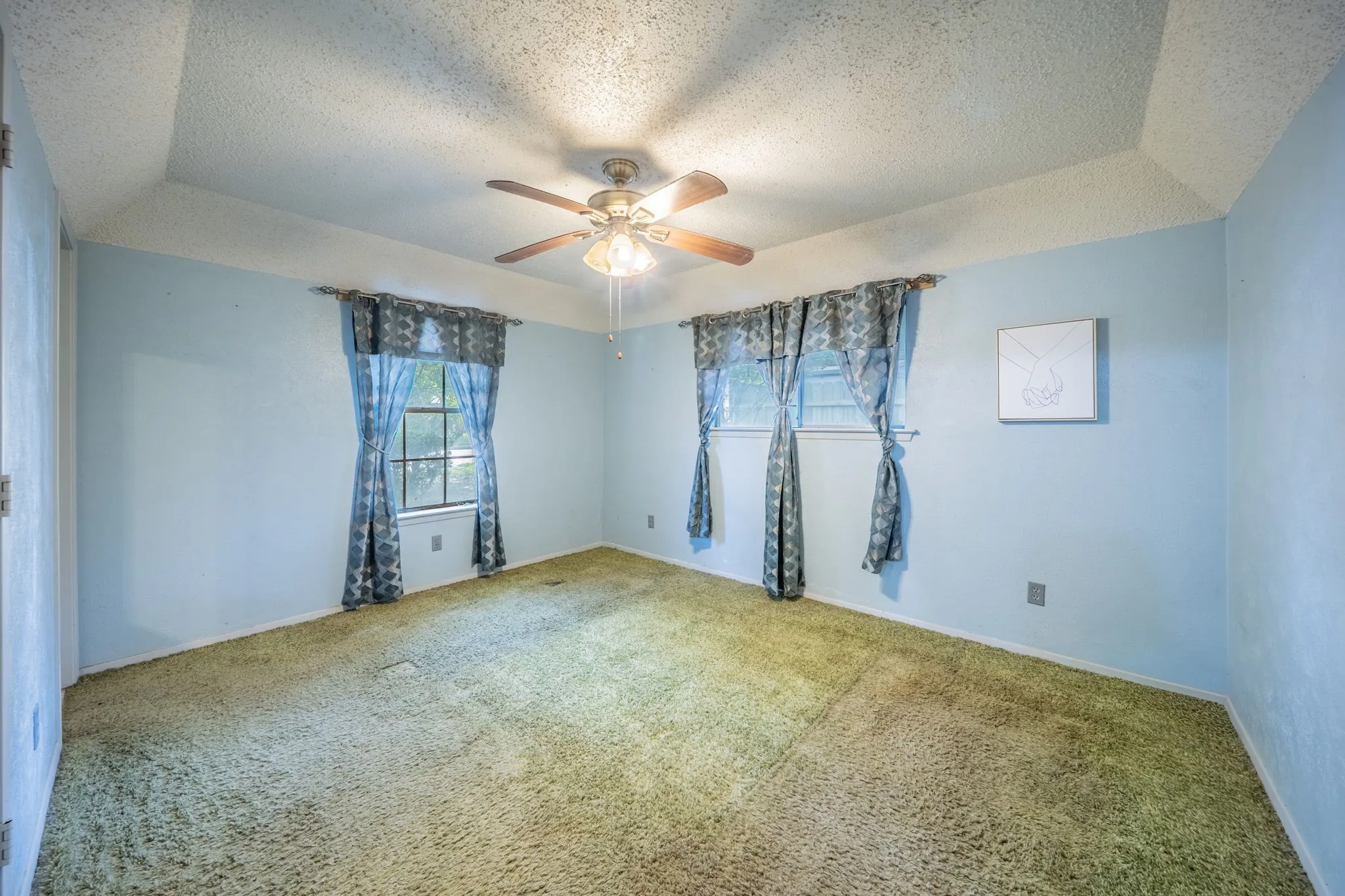 Recessed ceiling with a central ceiling fan, and two windows