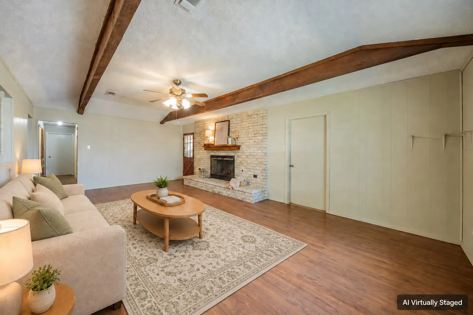 Living area featuring wood-finish flooring, exposed ceiling beams, and a stone-clad fireplace with a wood mantel