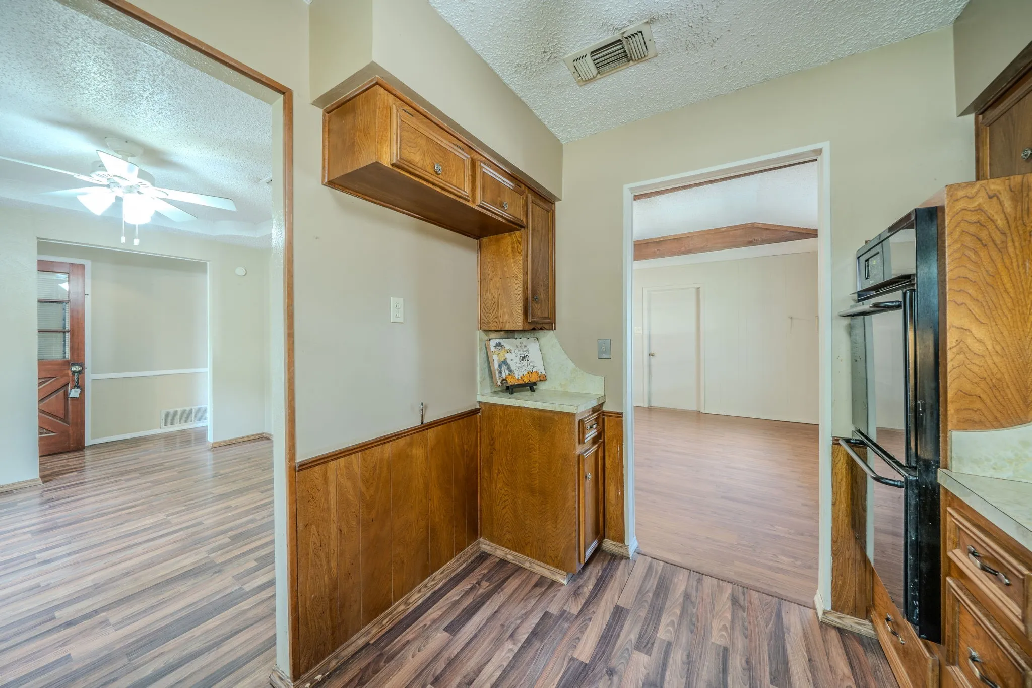 Wood-finish flooring throughout, wood paneling, and an integrated oven within wood cabinetry