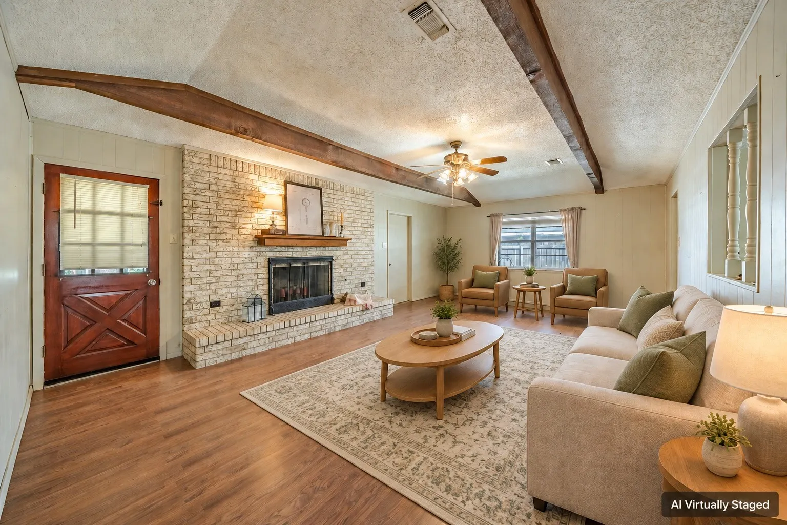 Living area featuring wood-finish flooring, exposed ceiling beams, a brick fireplace with a wood mantle, and a ceiling fan