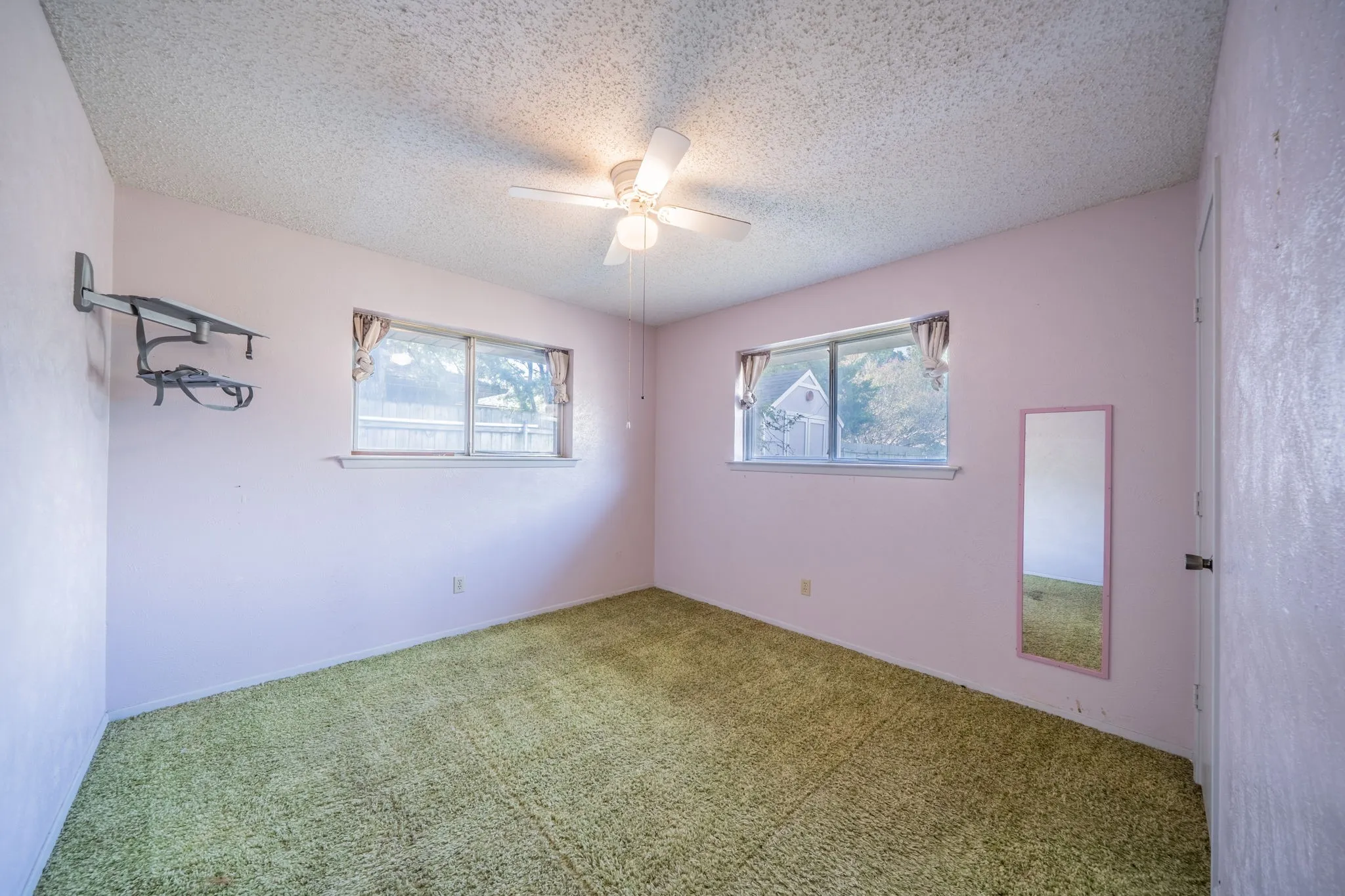 Dual windows with exterior views, ceiling fan, and wall-mounted shelving
