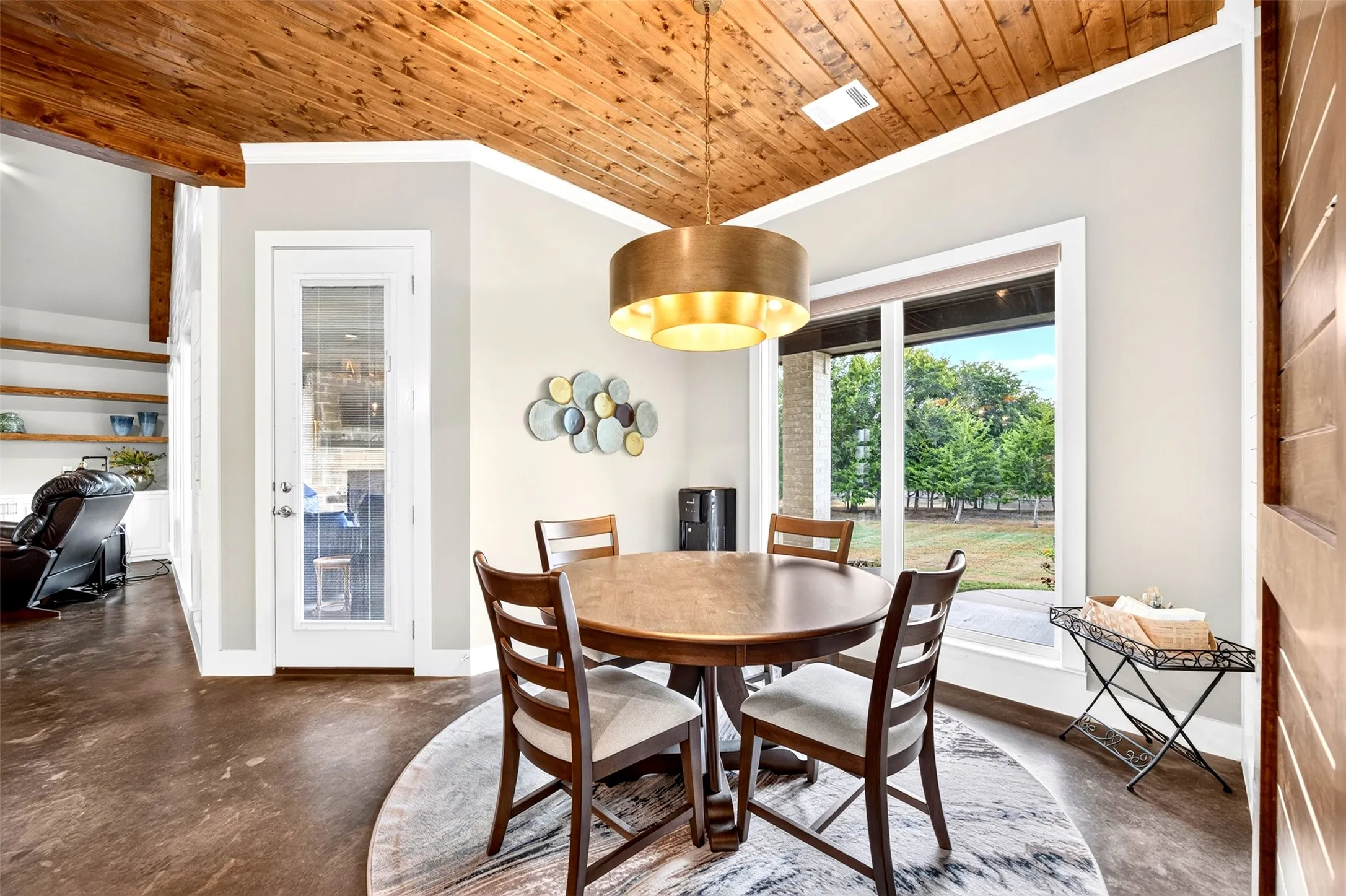 Beautiful dining area with designer lighting and large windows overlooking the gorgeous backyard