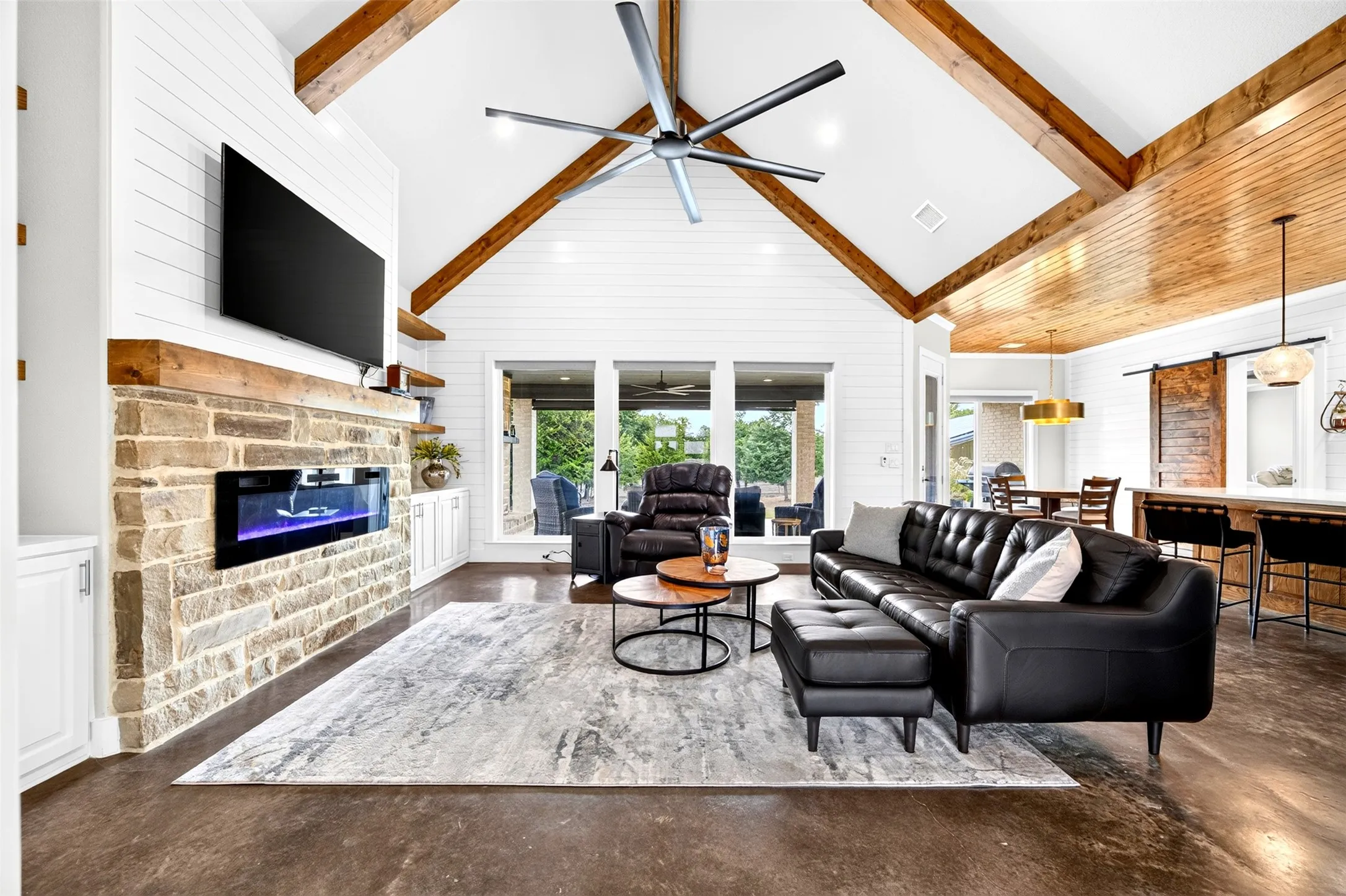 Living room with vaulted ceiling with beams, electric fireplace and electric shades