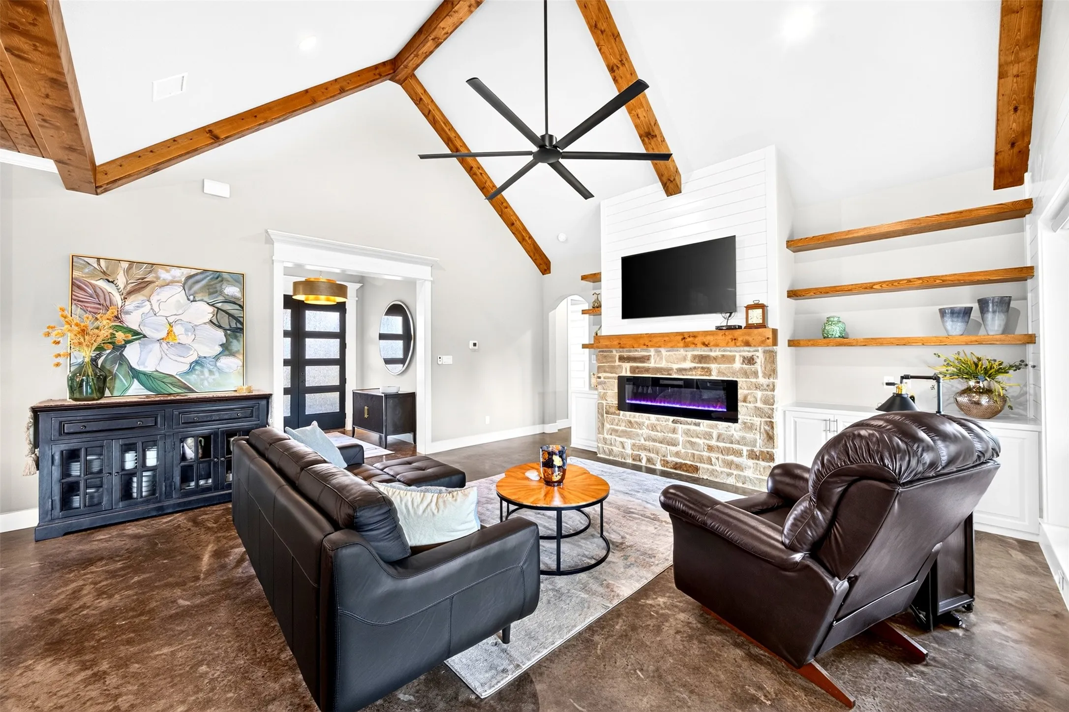 Living room with vaulted ceiling with beams, electric fireplace and electric shades