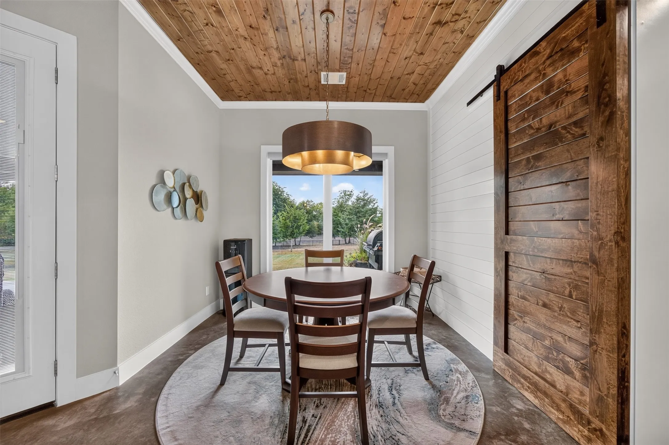 Beautiful dining area with wood ceiing, designer lighting and barn door