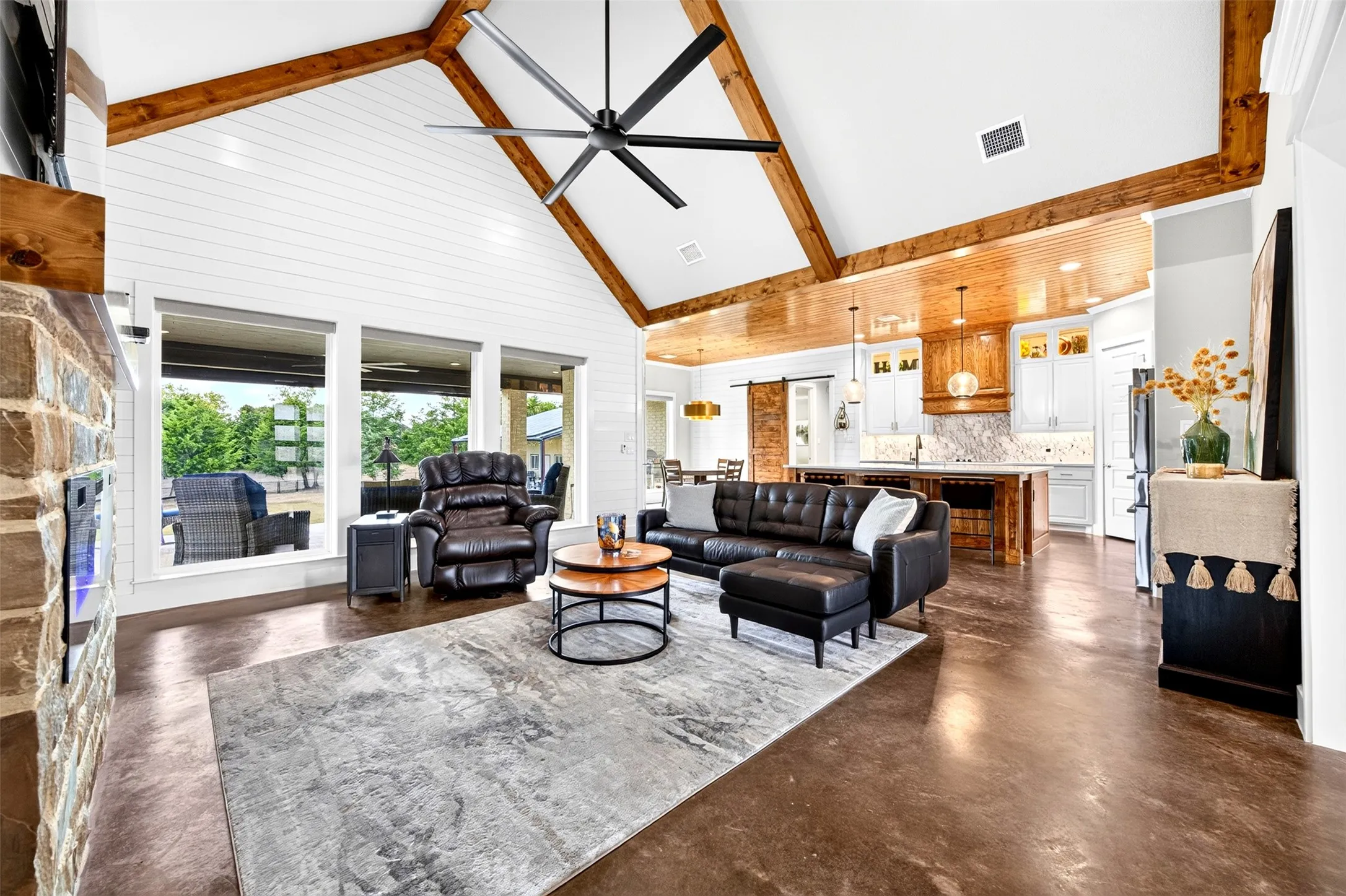Living room with vaulted ceiling with beams, electric fireplace and electric shades