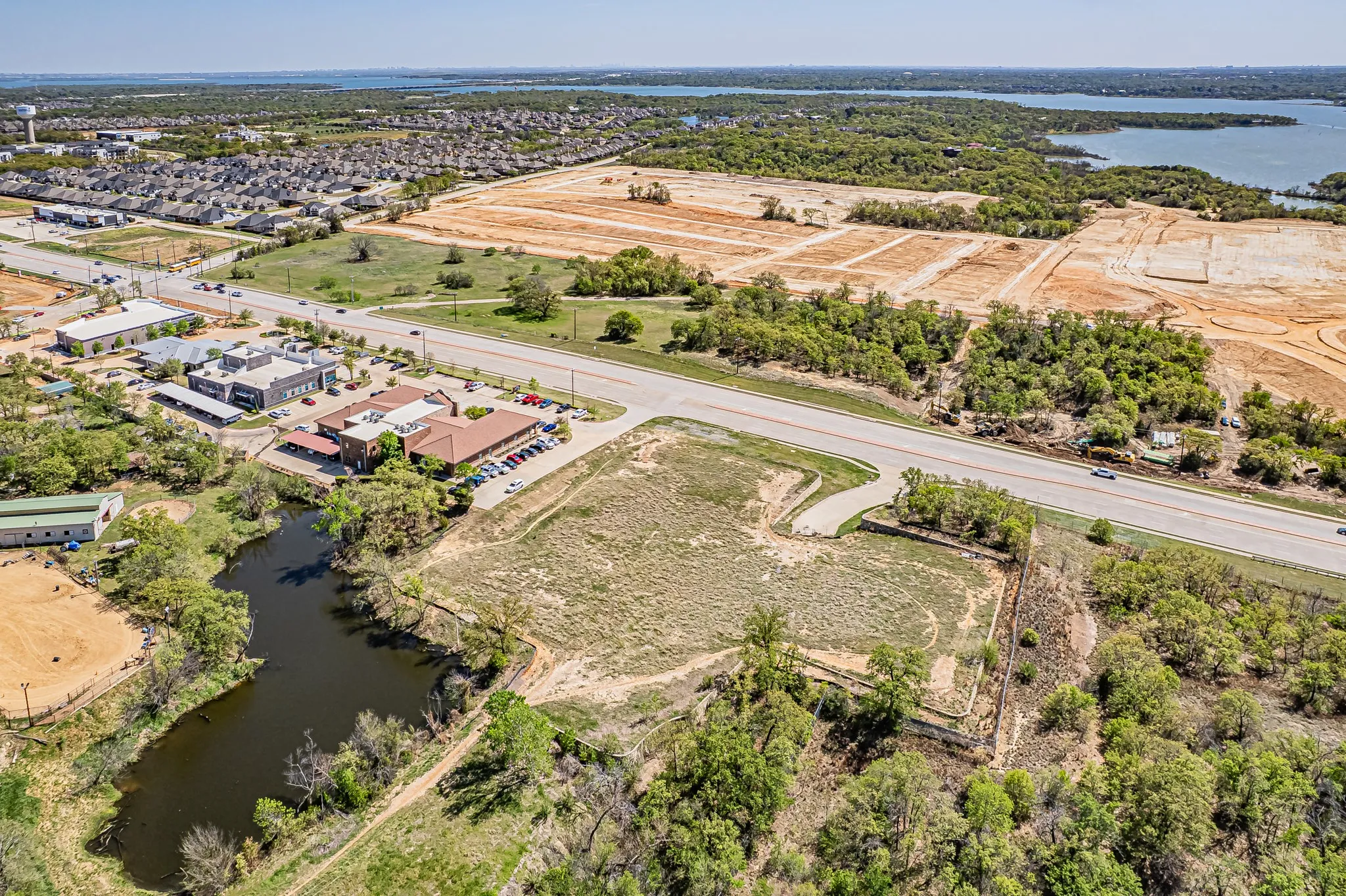 Aerial perspective showcasing surrounding natural landscape with bodies of water, undeveloped land, and established commercial structures