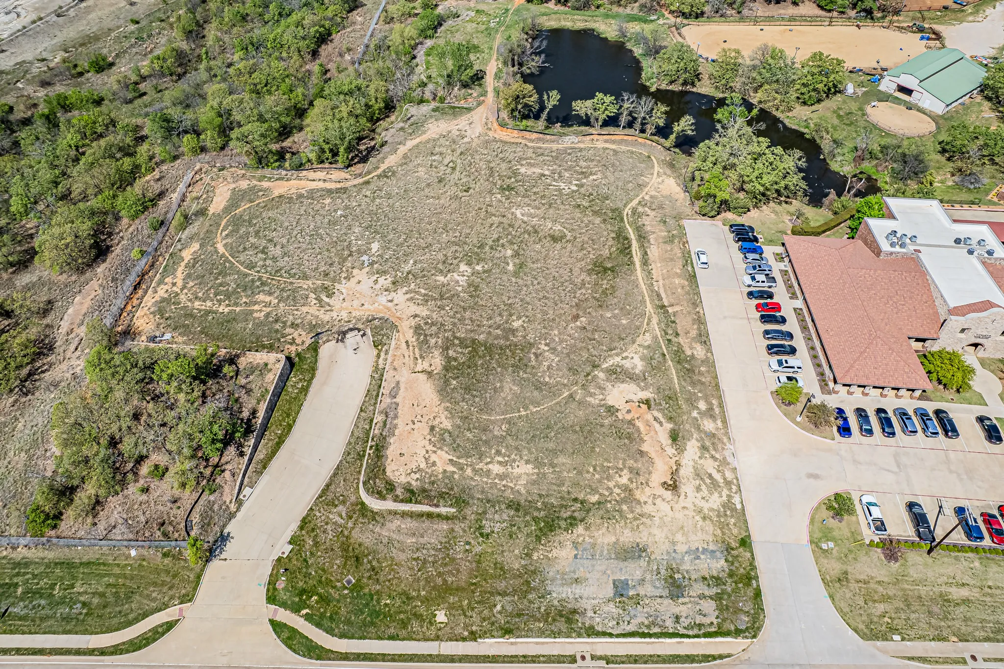 Expansive undeveloped land with a paved access road and a water feature at the property's edge