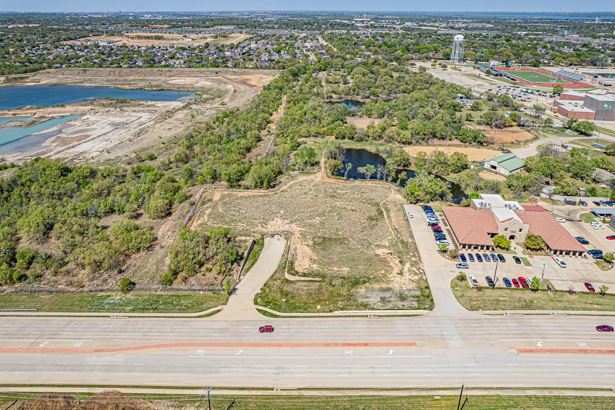 Expansive undeveloped land featuring a cleared building area, direct road frontage, and established tree lines