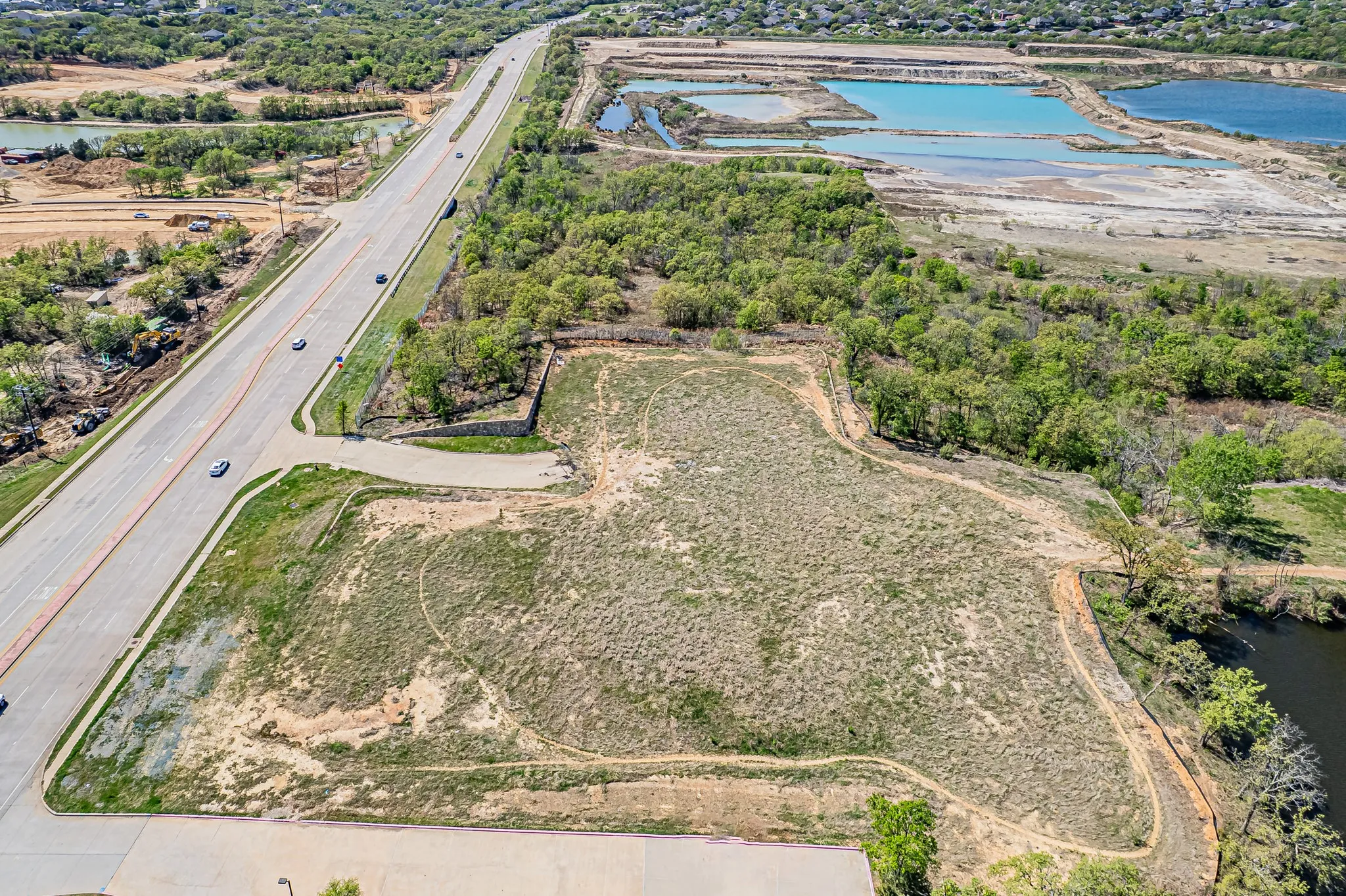 Expansive land parcel featuring direct road frontage, perimeter trees, and proximity to water features