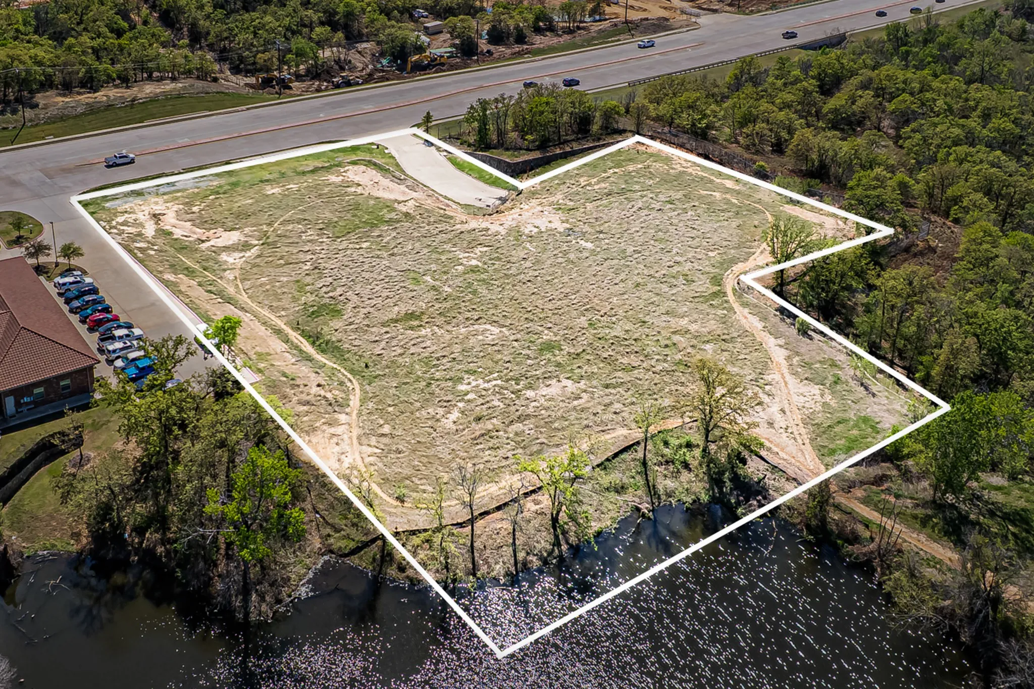 Expansive undeveloped land with a defined boundary, bordering a body of water and a paved road