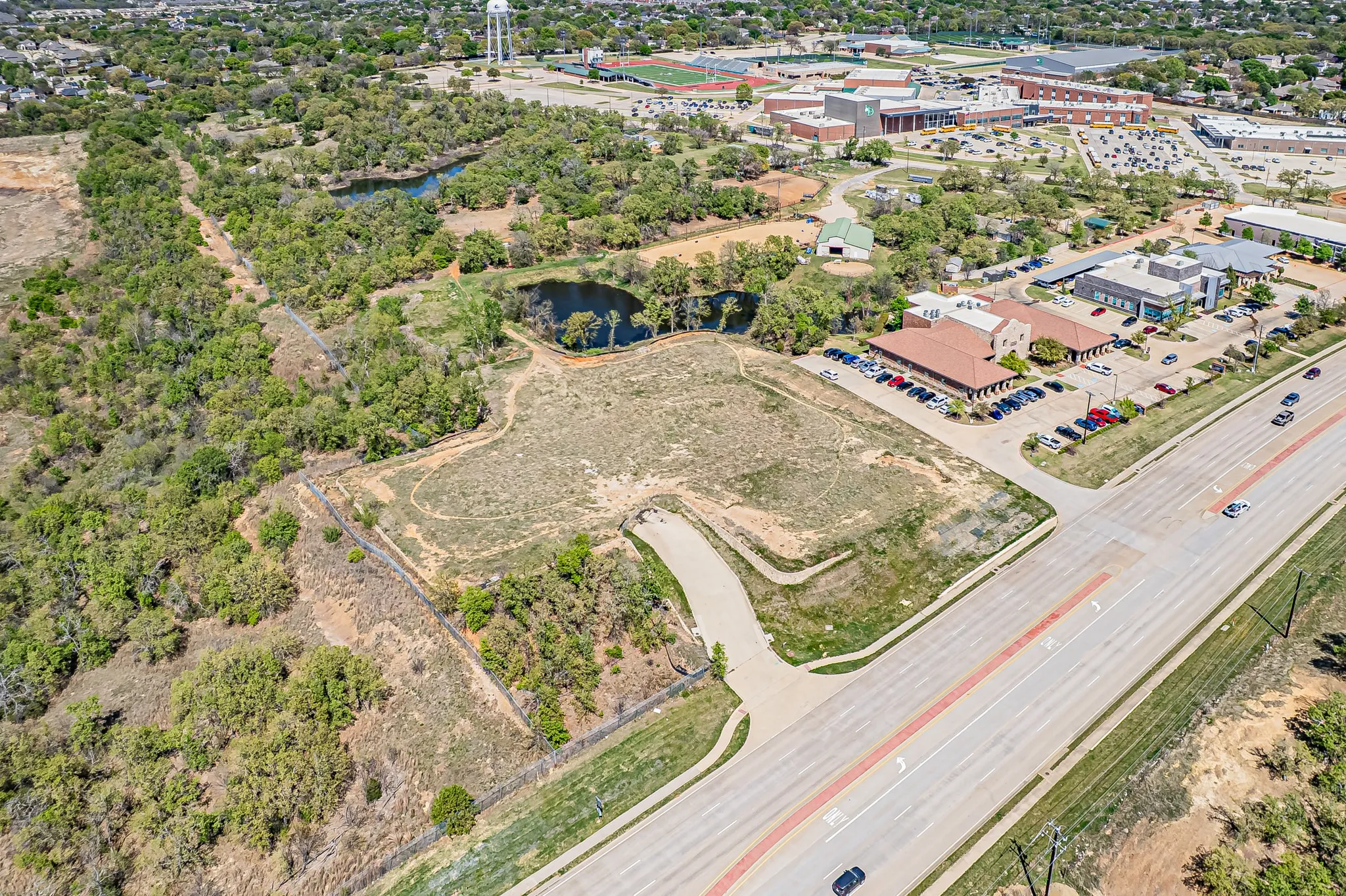 Expansive land parcel featuring direct road frontage, multiple adjacent buildings, and two distinct water features