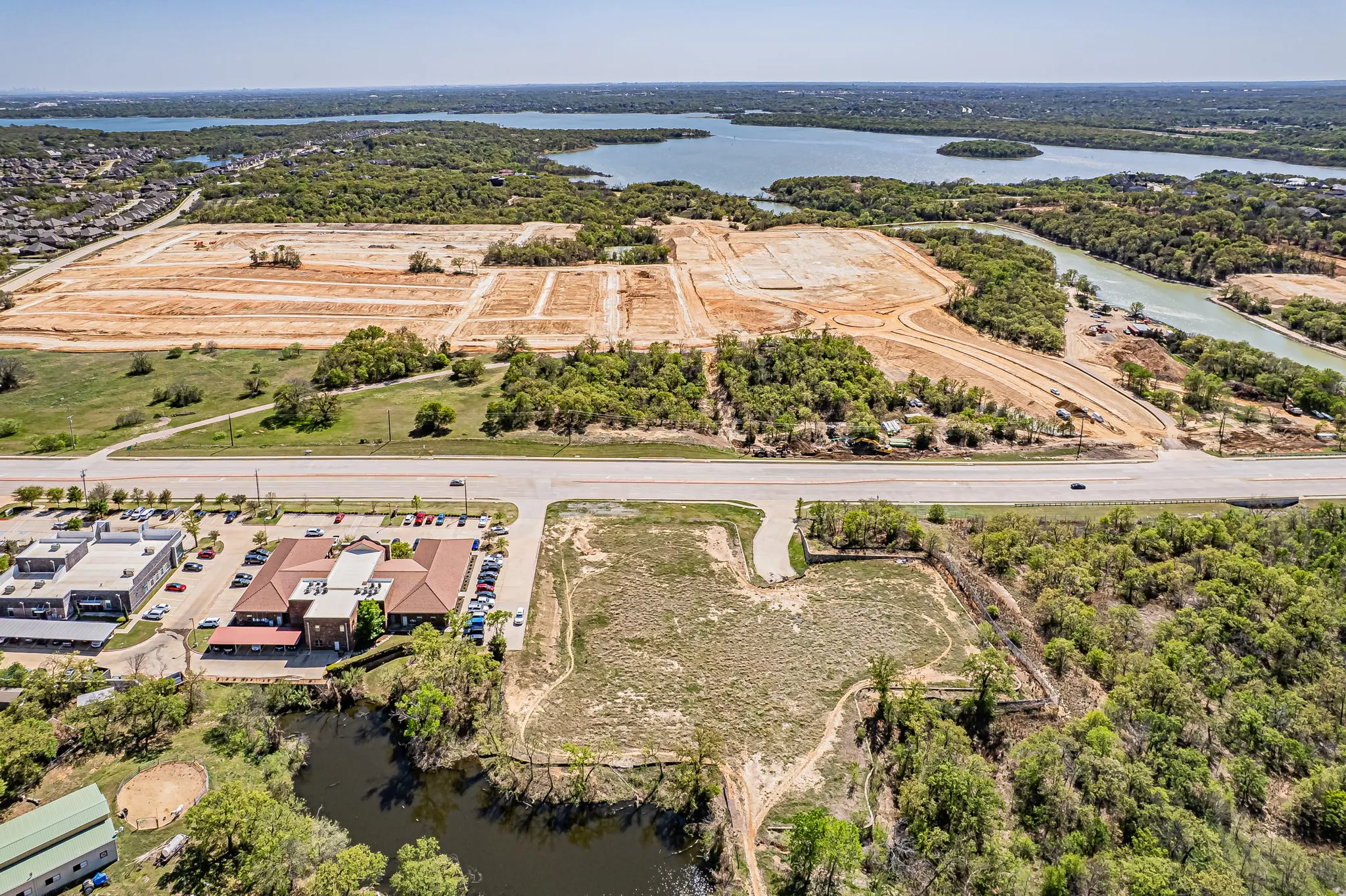 Expansive land parcel featuring direct road frontage, surrounded by mature trees, and positioned near a large body of water