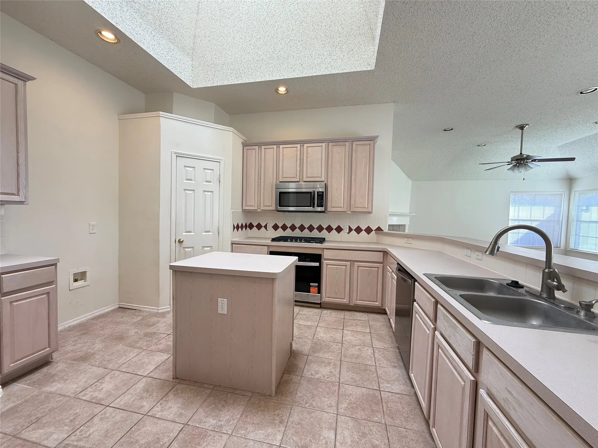 Kitchen featuring a center island, recessed lighting, skylight, tile flooring, and stainless steel appliances