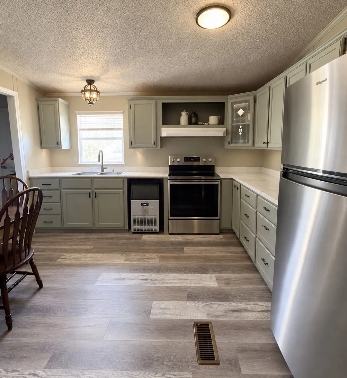 Kitchen featuring extensive cabinetry, stainless steel appliances, wood-finish flooring, and solid surface countertops. Ice maker will be removed and dishwasher installed.