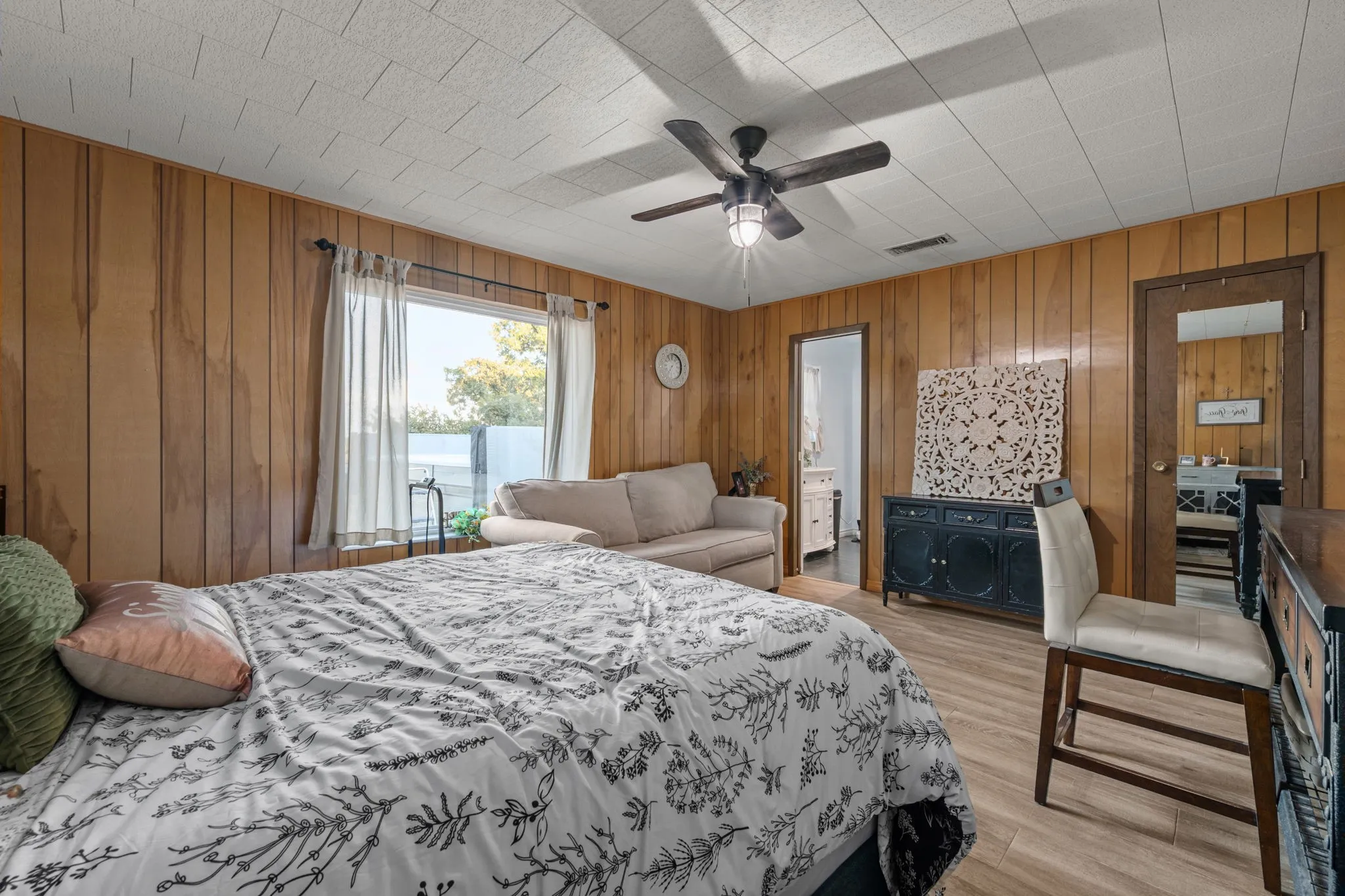 Wood-finish paneling, drop ceiling with recessed lighting and ceiling fan, wood-finish flooring, and window with natural light