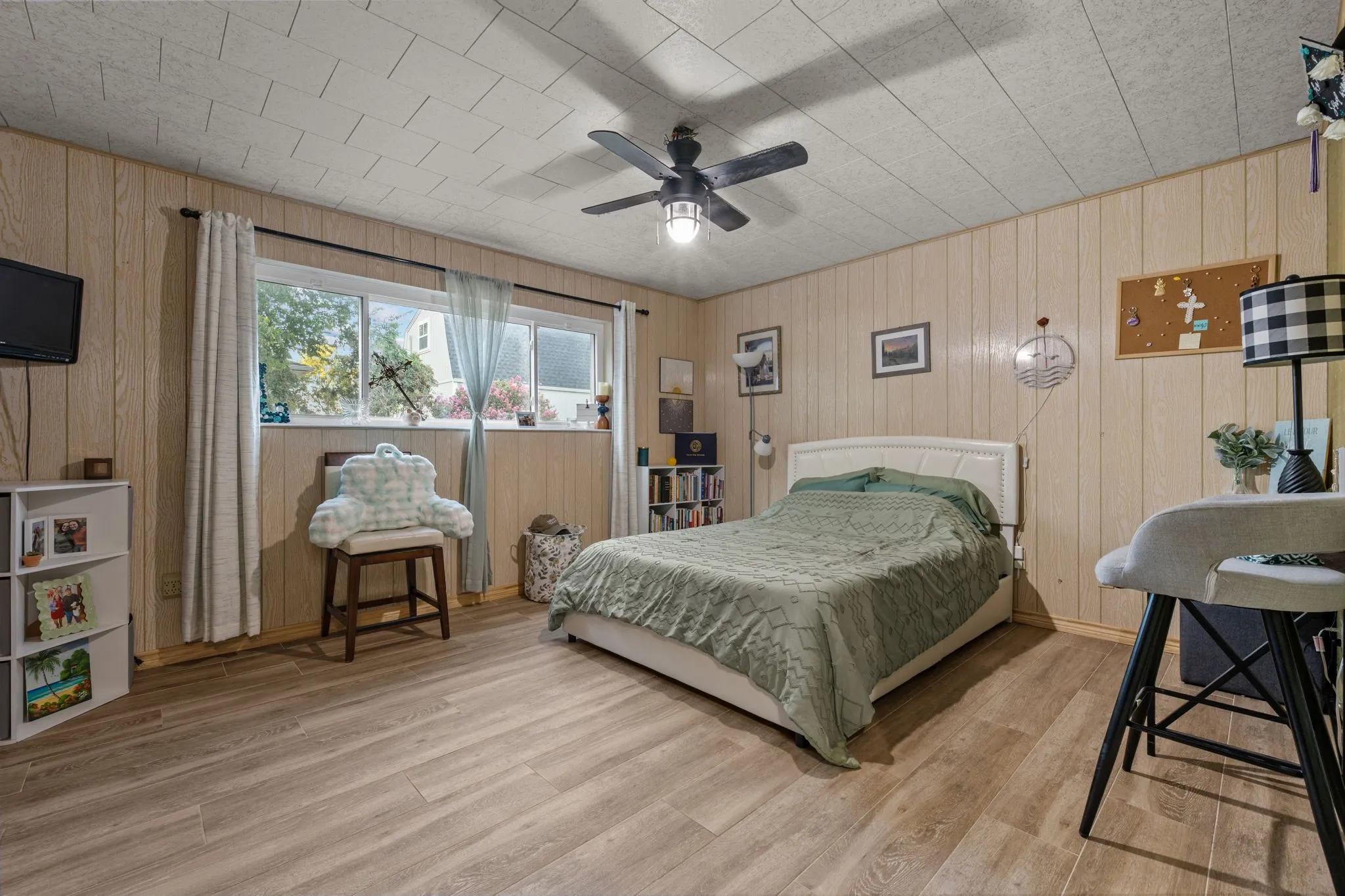 Wood-finish flooring, paneled walls, and a ceiling fan with integrated lighting
