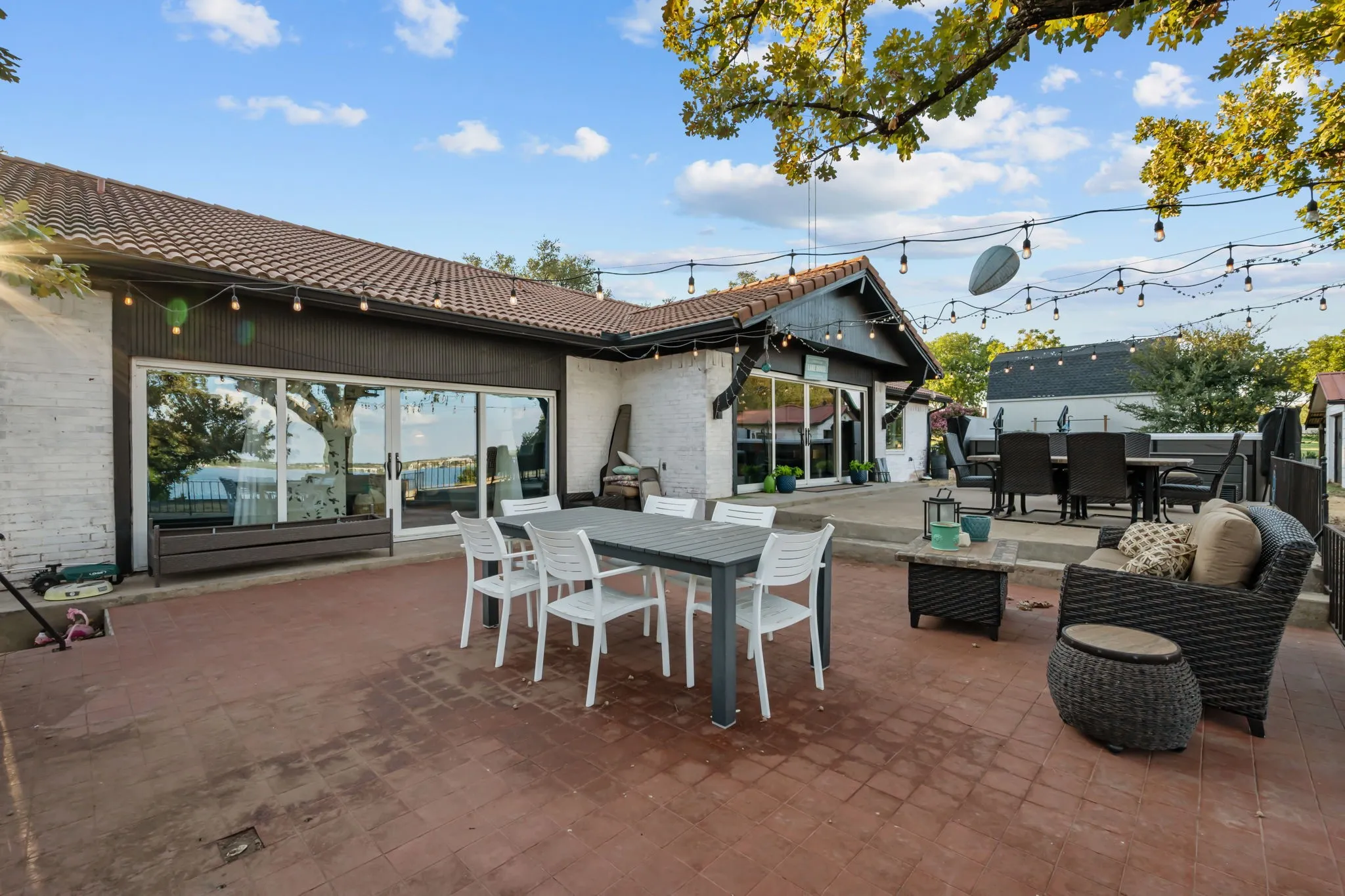 Expansive brick paver patio with multiple entertainment areas, a tile roof, and large sliding glass doors