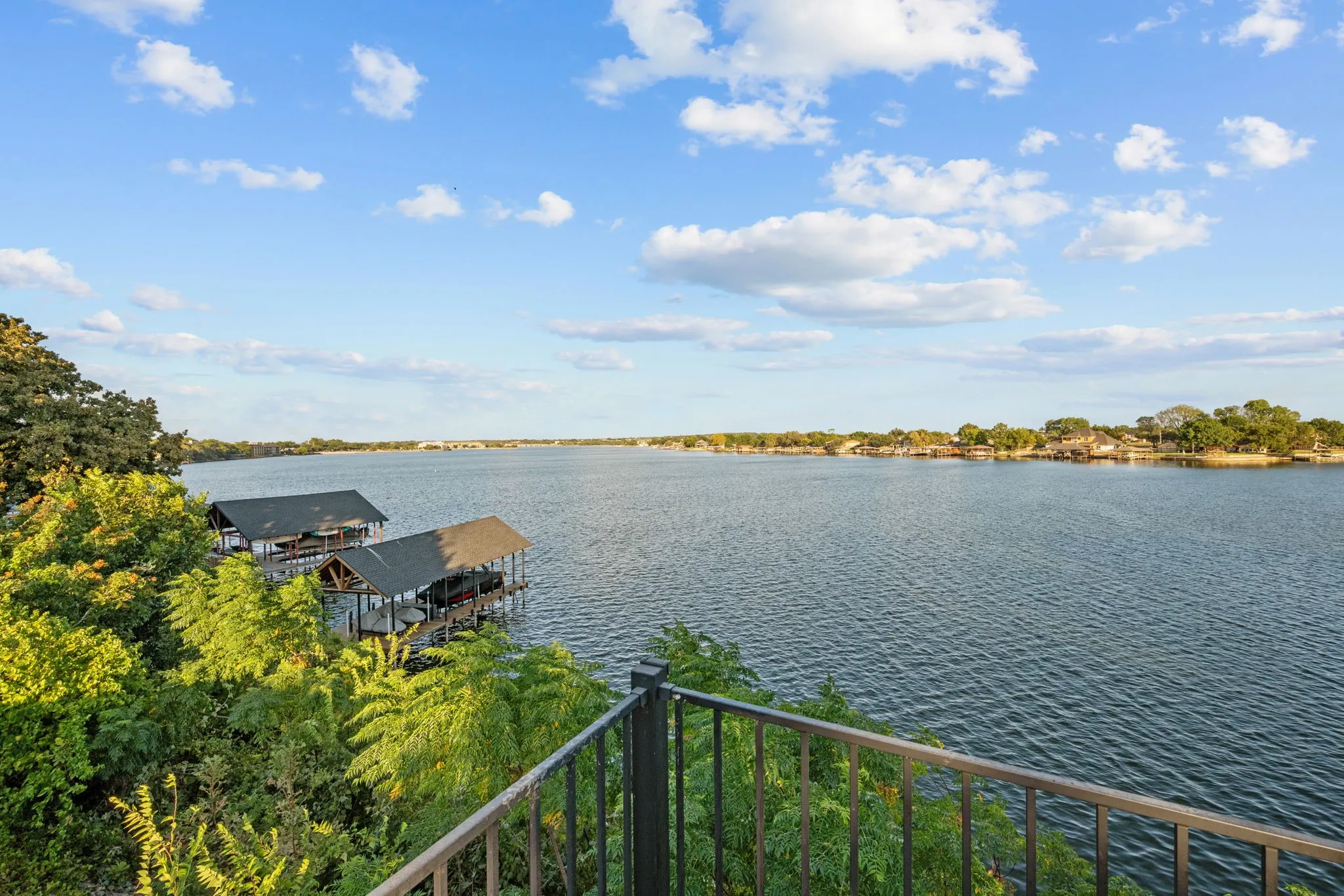 Expansive waterfront with distant shoreline, boat docks, and lush perimeter foliage