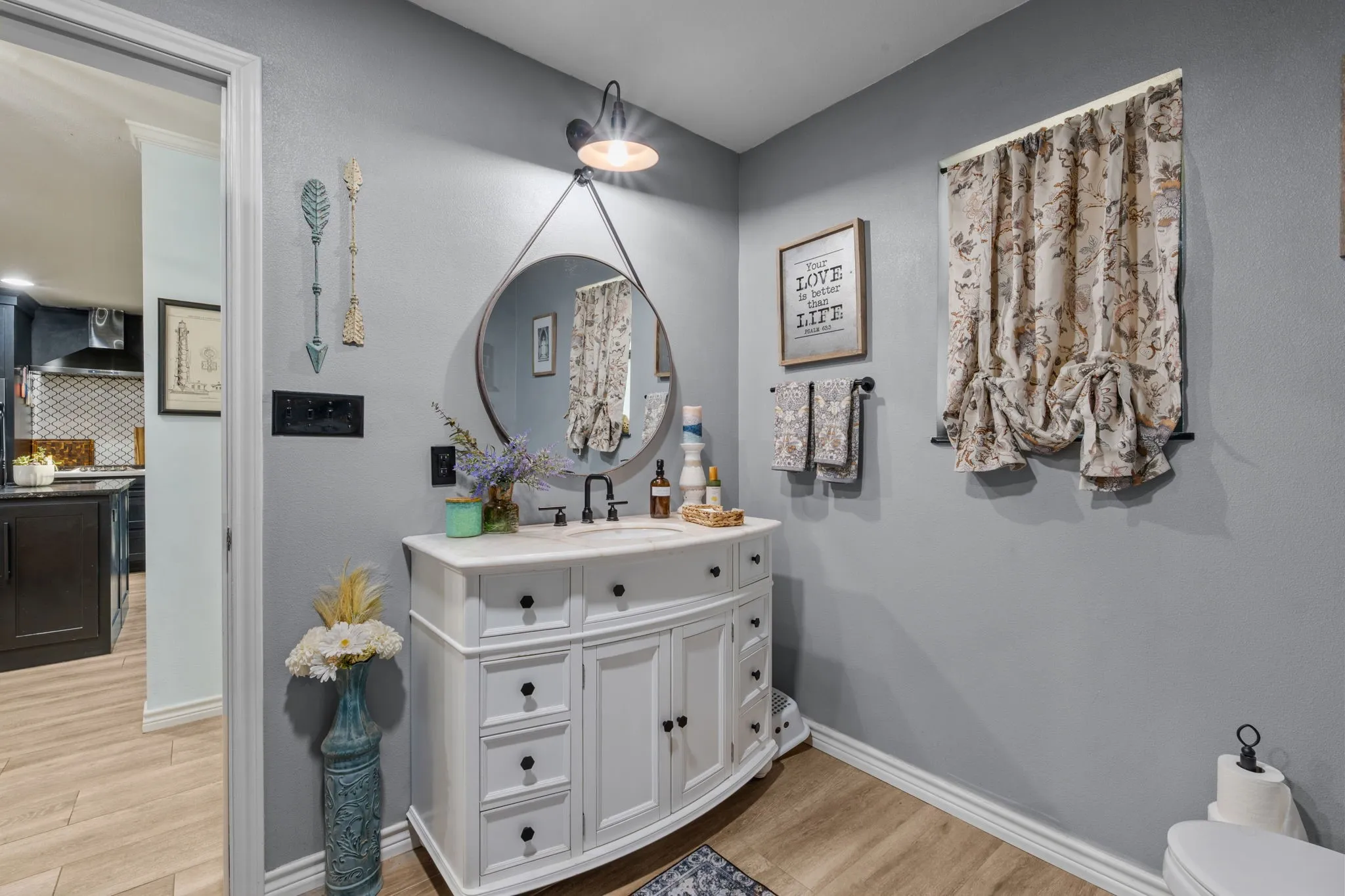 White vanity with integrated sink, black faucet, and round mirror