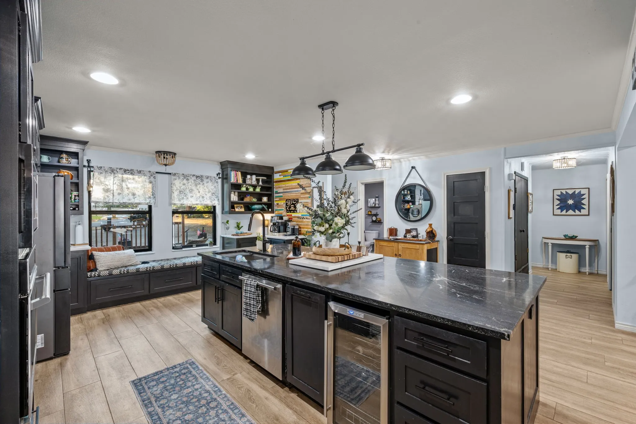 Kitchen featuring a large central island with a stone countertop, recessed lighting, wood-finish flooring, a built-in window bench, and dark cabinetry