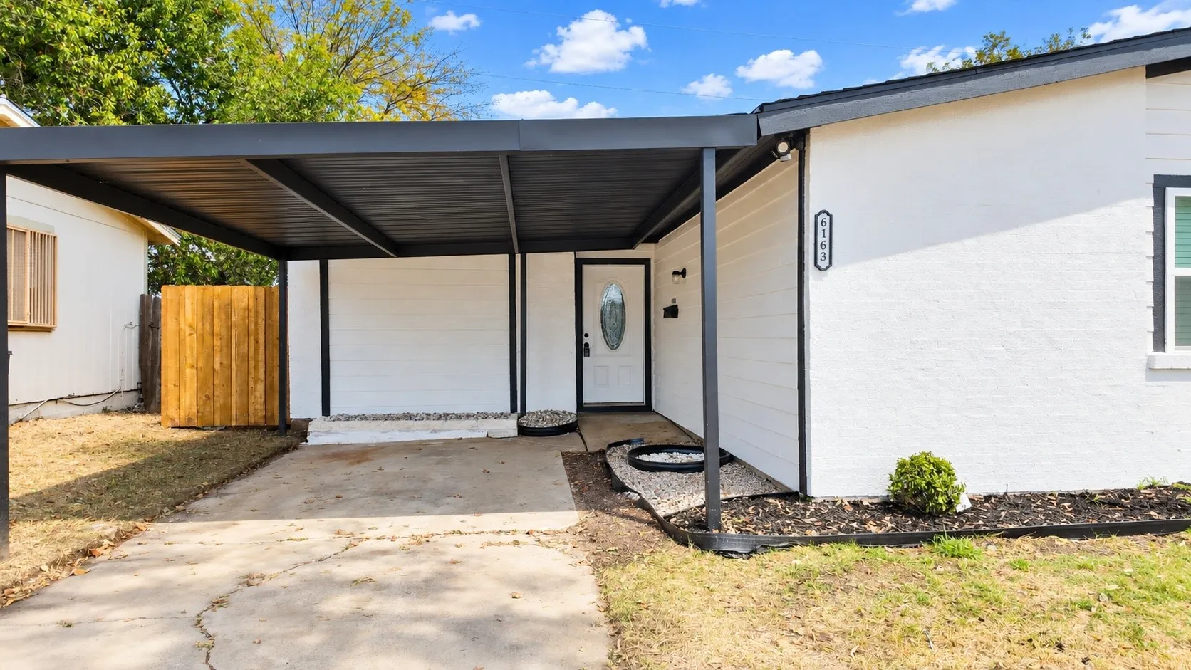 Covered carport and converted garage exterior with the existing rock border and entry details.