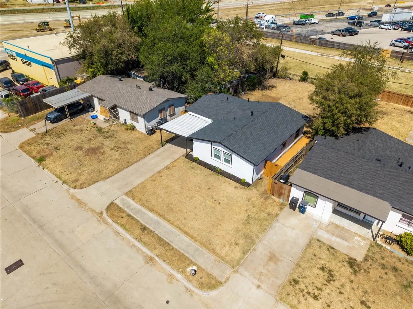Drone view of the property and surrounding lots with the home's driveway and covered carport.