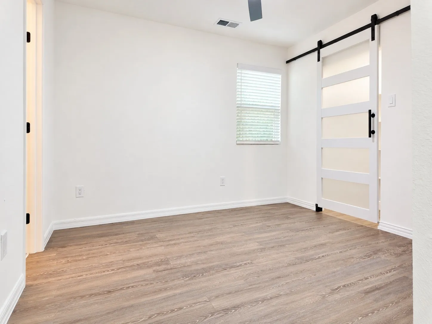 Primary bedroom with hard-surface flooring and sliding barn-style closet access.
