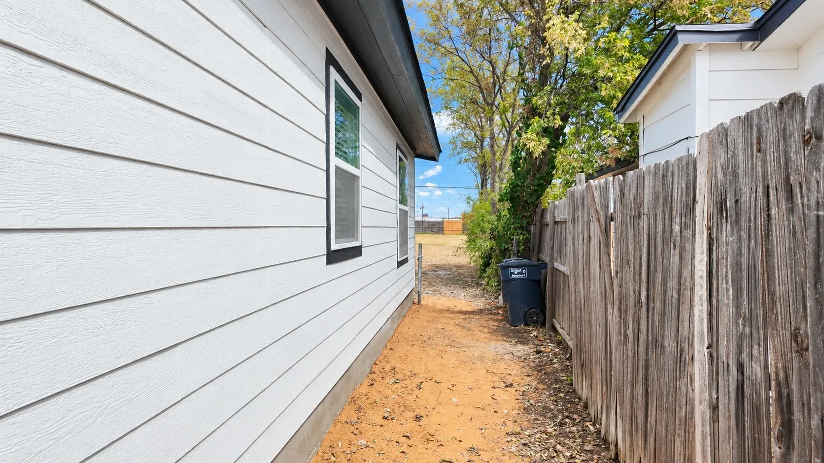 Side-yard passage with exterior windows, fencing, and access toward the backyard.