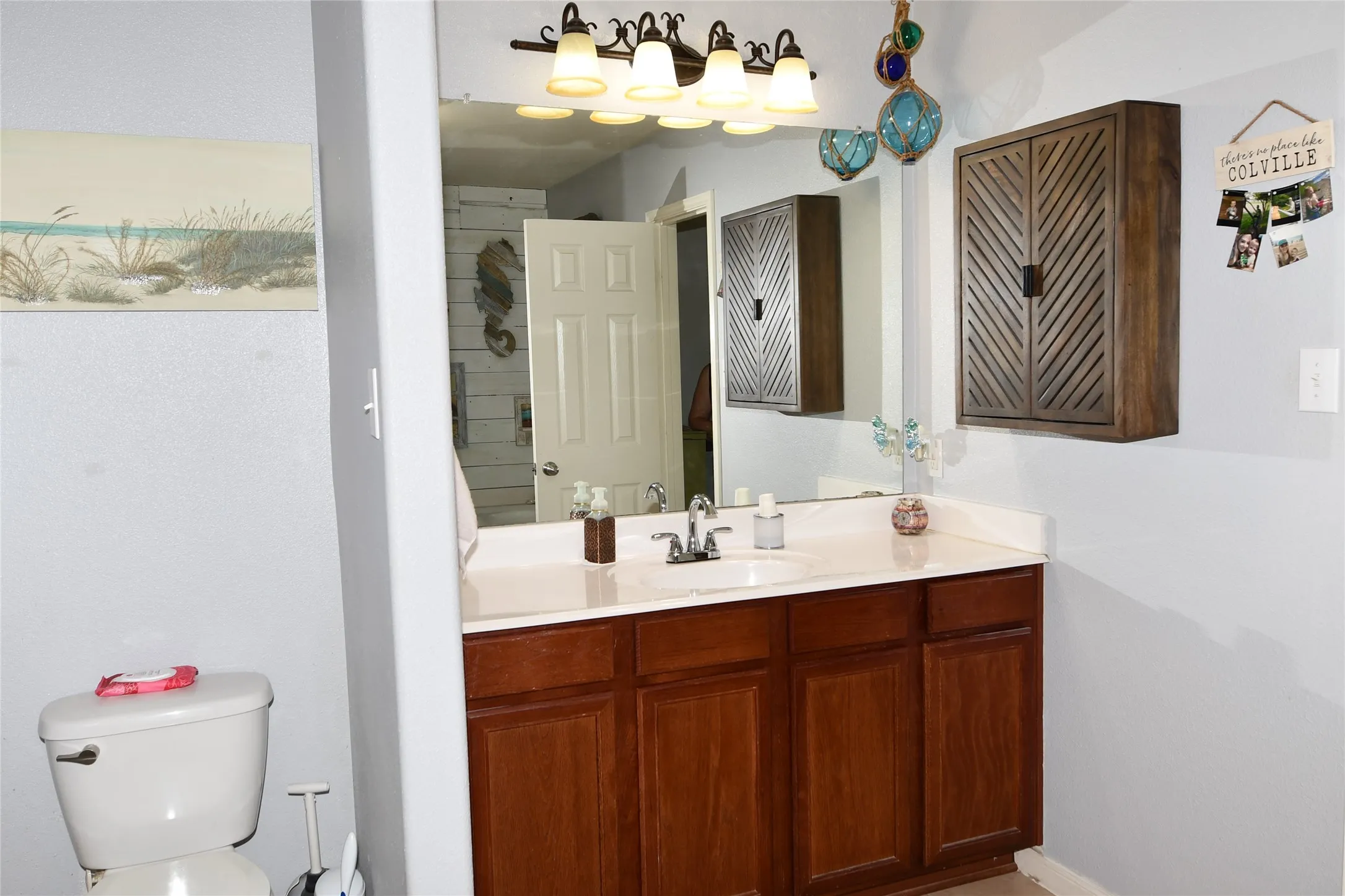 Vanity with wood-finish cabinetry, white countertop, and integrated sink